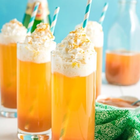 Three glasses of a caramel apple drink with a blue background