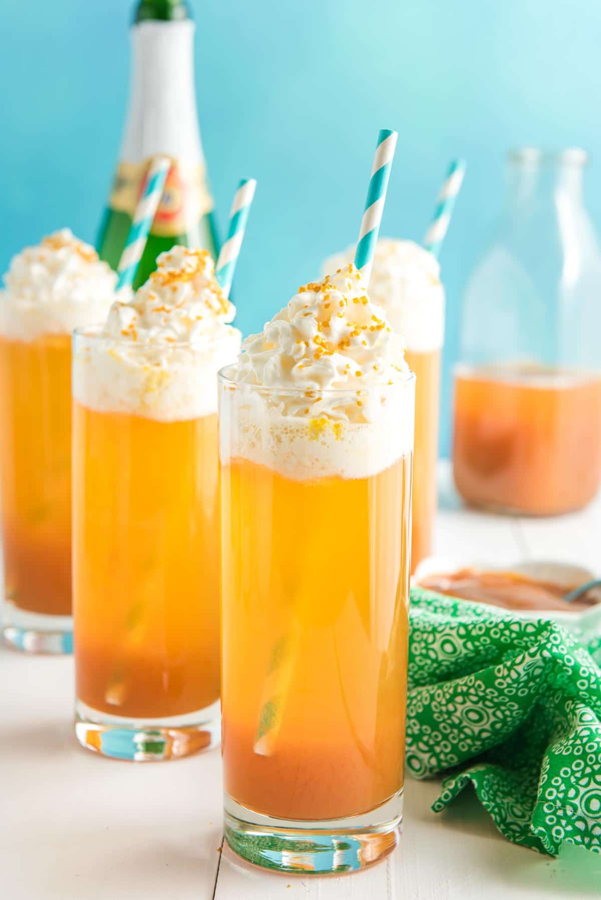 Three glasses of a caramel apple drink with a blue background