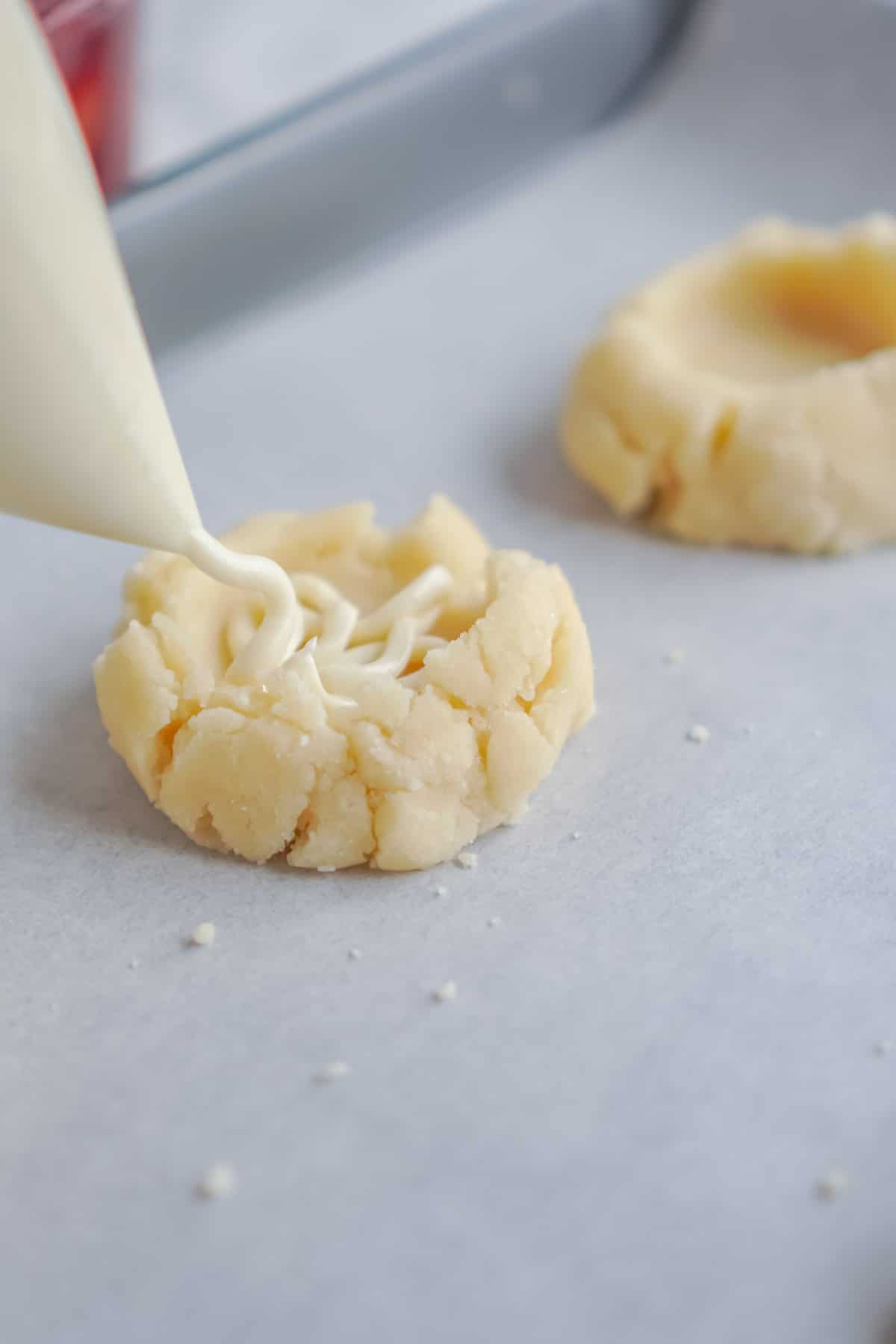Cheesecake filling being piped onto a sugar cookie