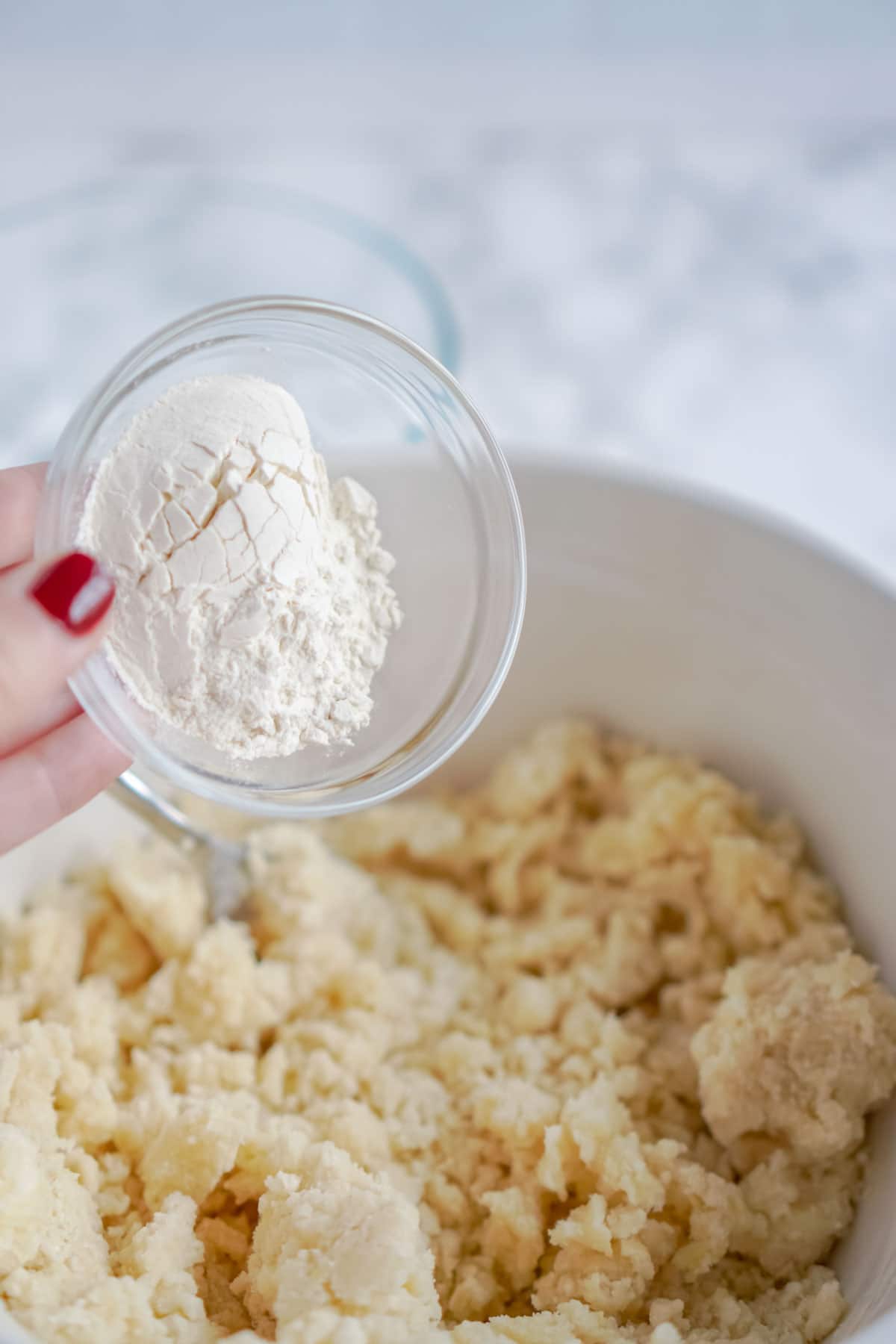 Woman's hand adding flour to sugar cookie mix