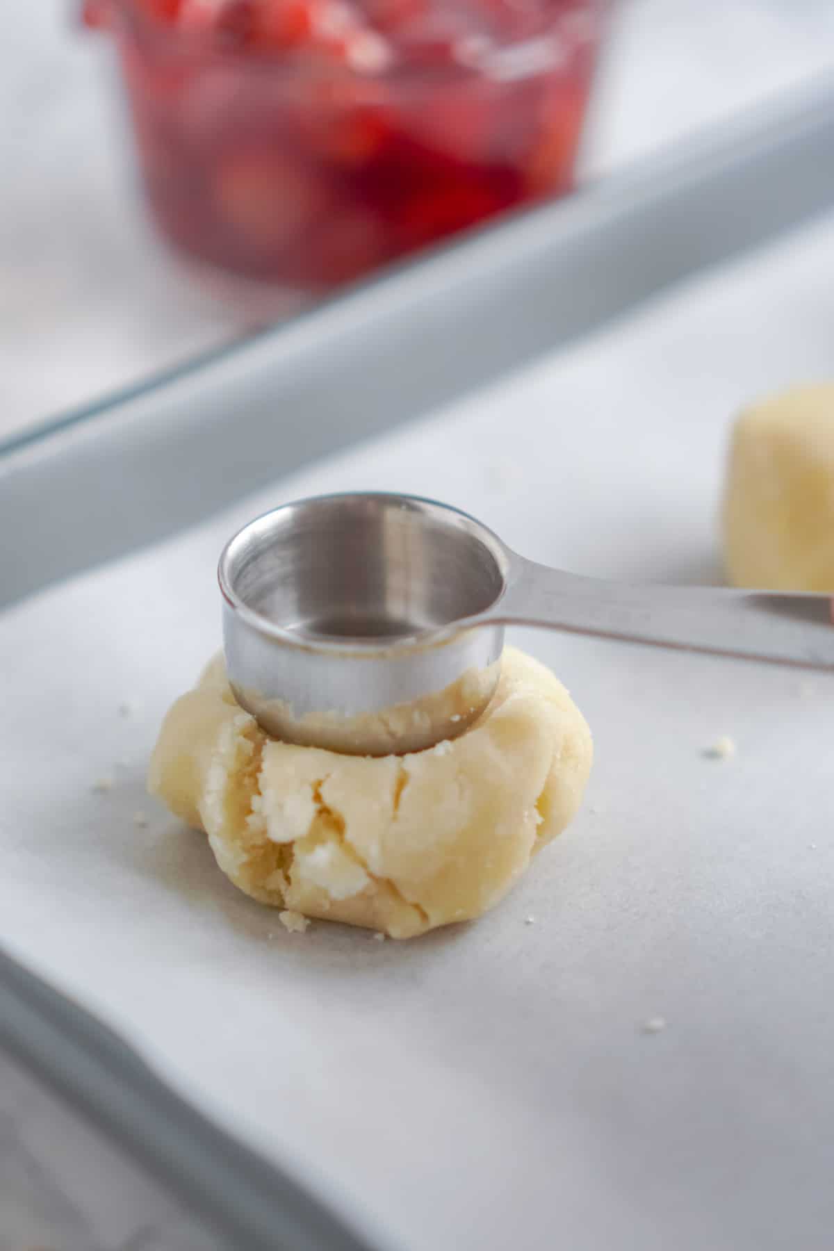 Metal measuring spoon pressing on sugar cookie dough