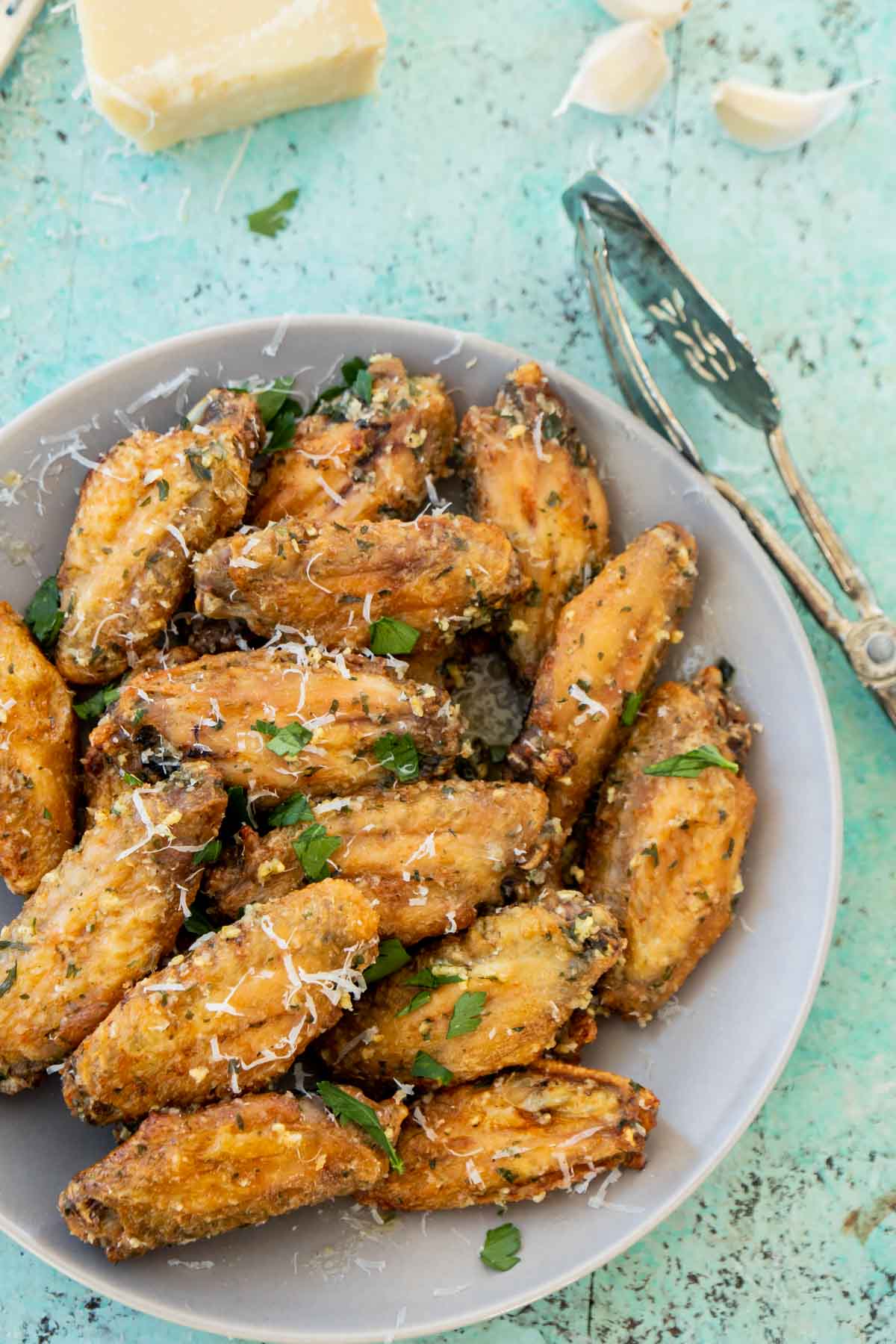 Plate of garlic parmesan wings with a block of parmesan