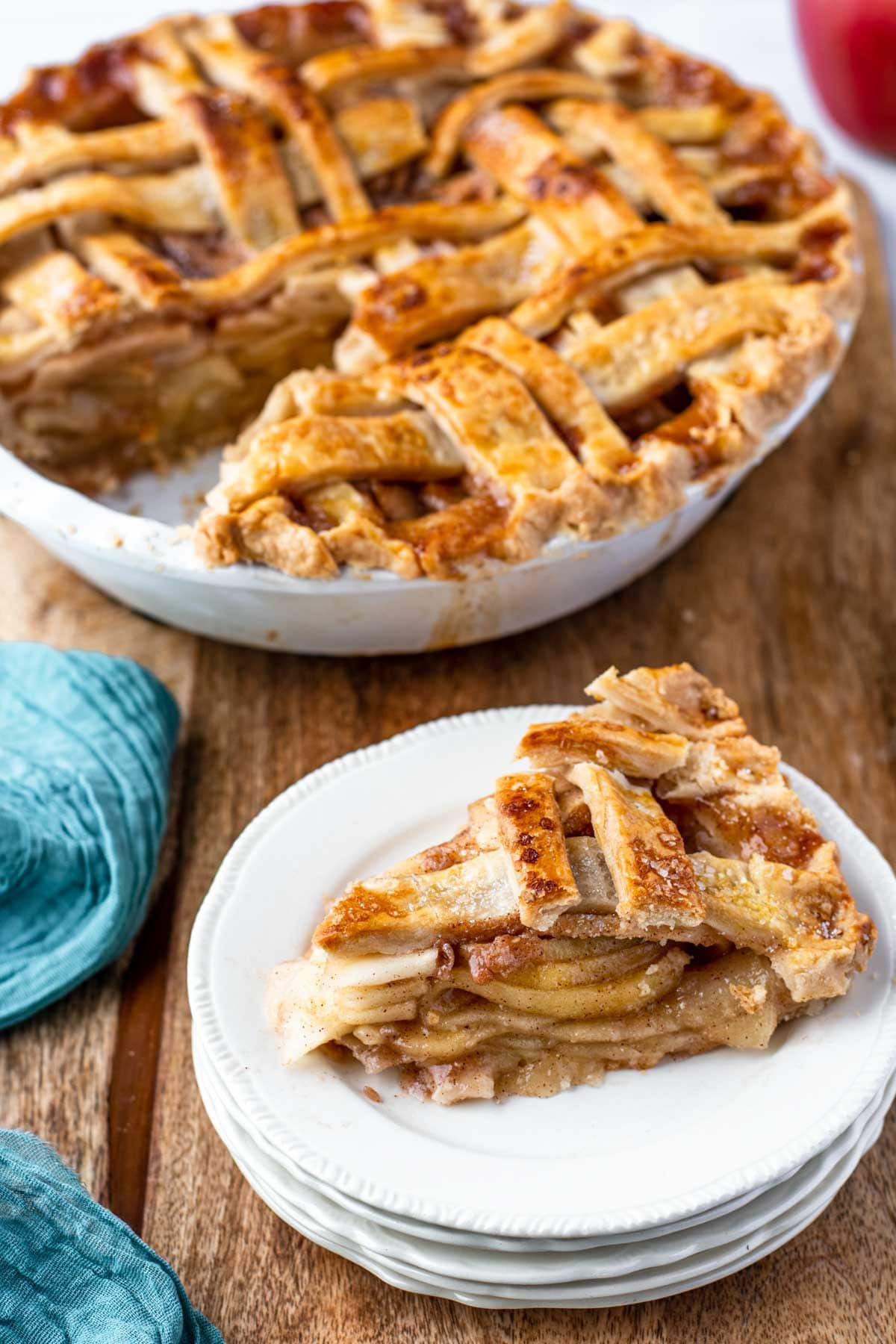 A slice of homemade apple pie on a stack of white plates