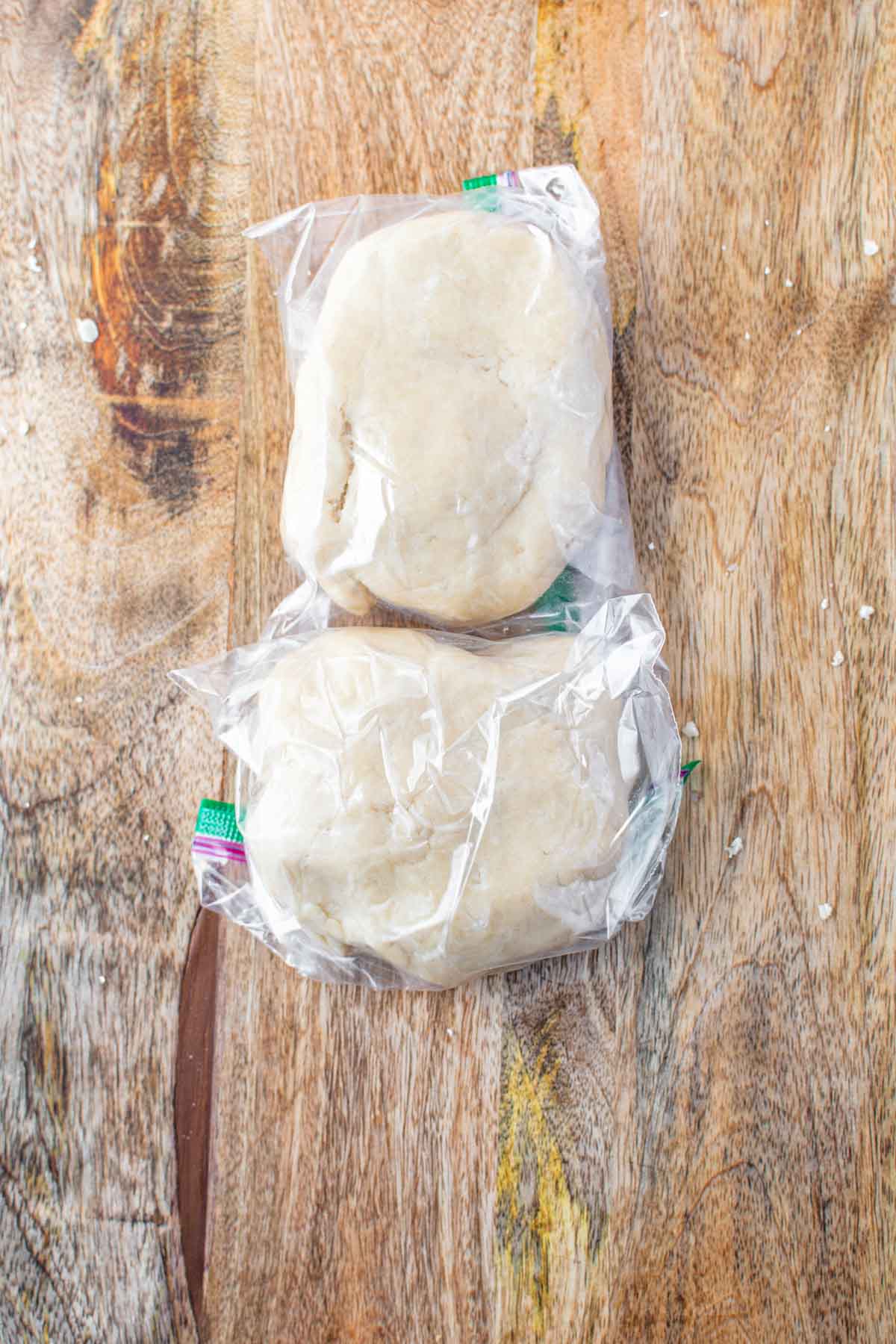 Two balls of homemade apple pie crust in plastic wrap