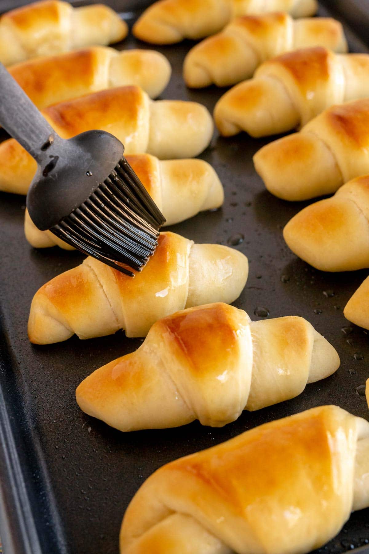 Silicone brush brushing crescent rolls with butter