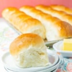 A homemade yeast roll on a stack of white plates