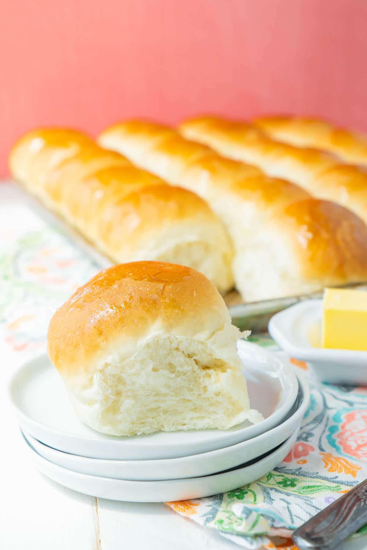 A homemade yeast roll on a stack of white plates