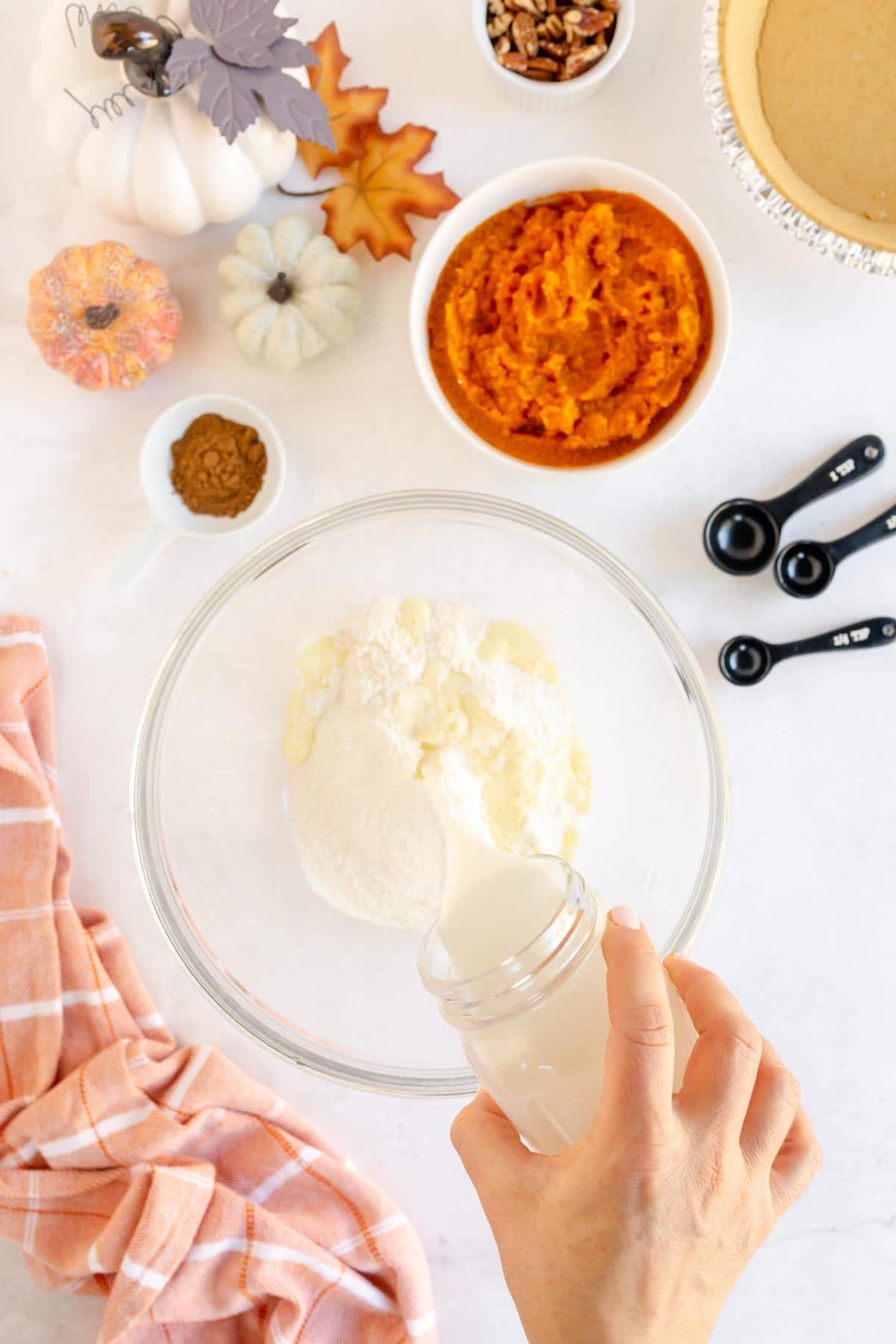 Woman's hand pouring milk into a bowl with pie filling