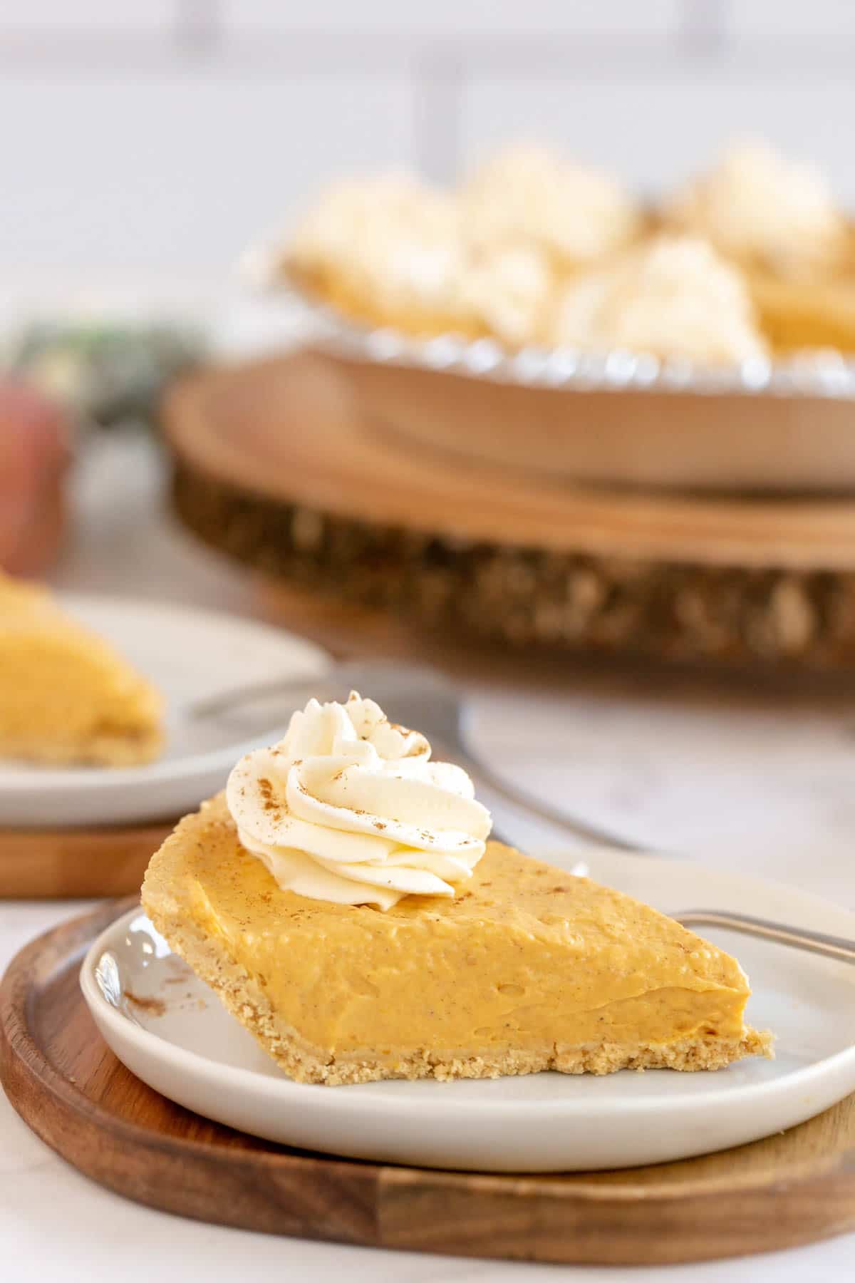 A piece of no bake pumpkin pie with the rest of the pie in the background