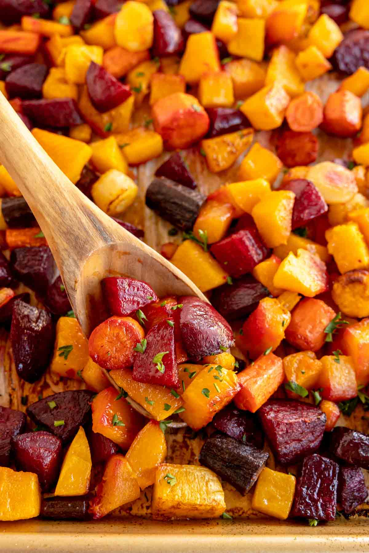 pan of roasted root vegetables with a wooden spoon 