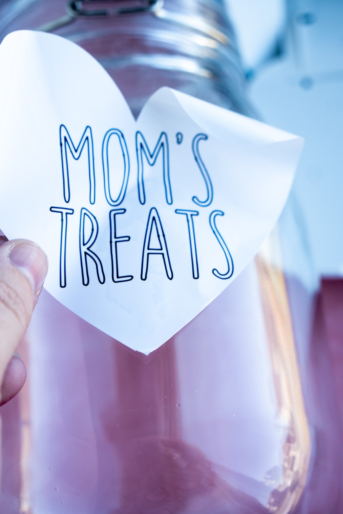 Woman's hand placing a mom's treats label on a jar