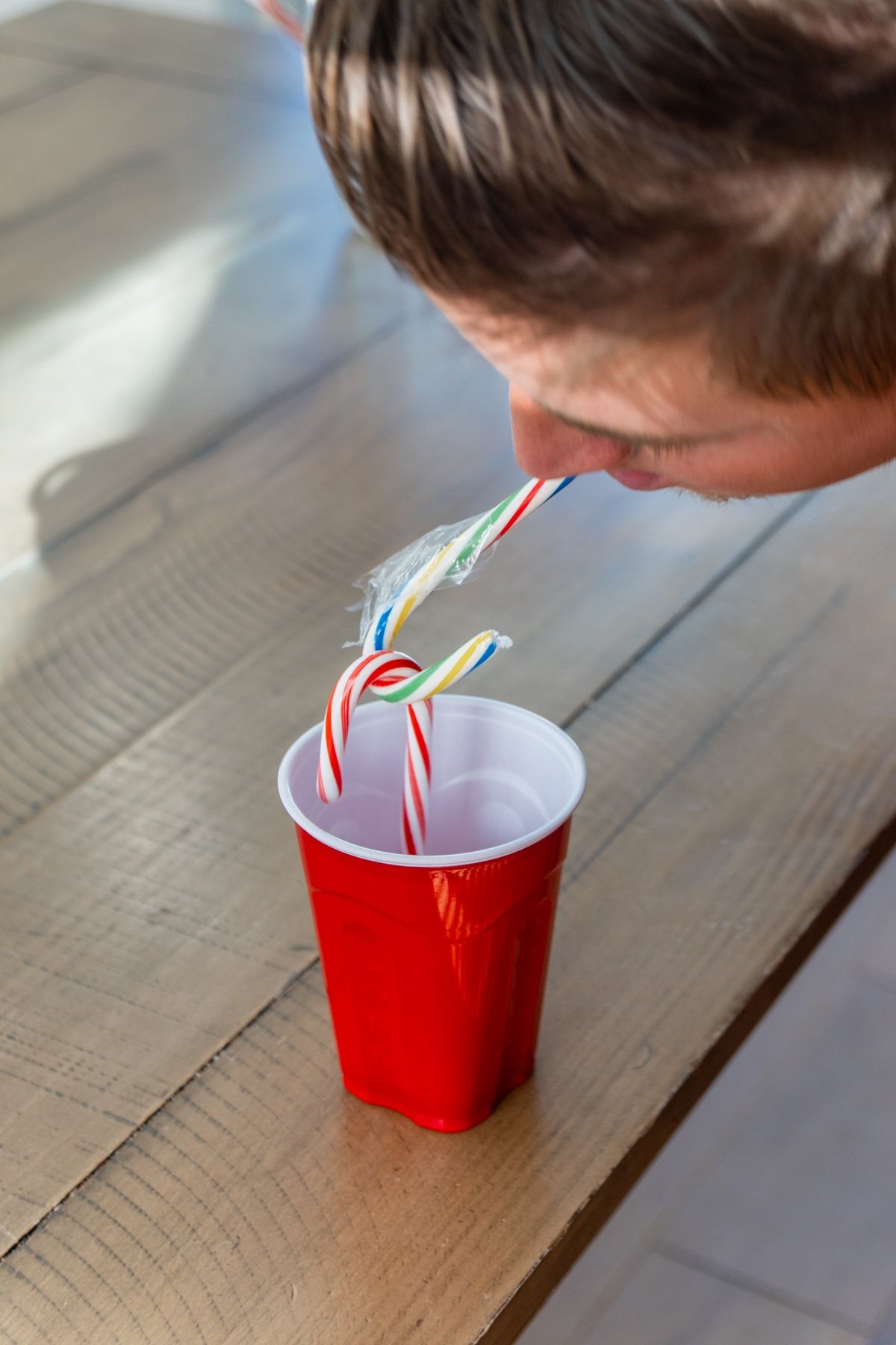 Man with a candy cane in his mouth and two other candy canes