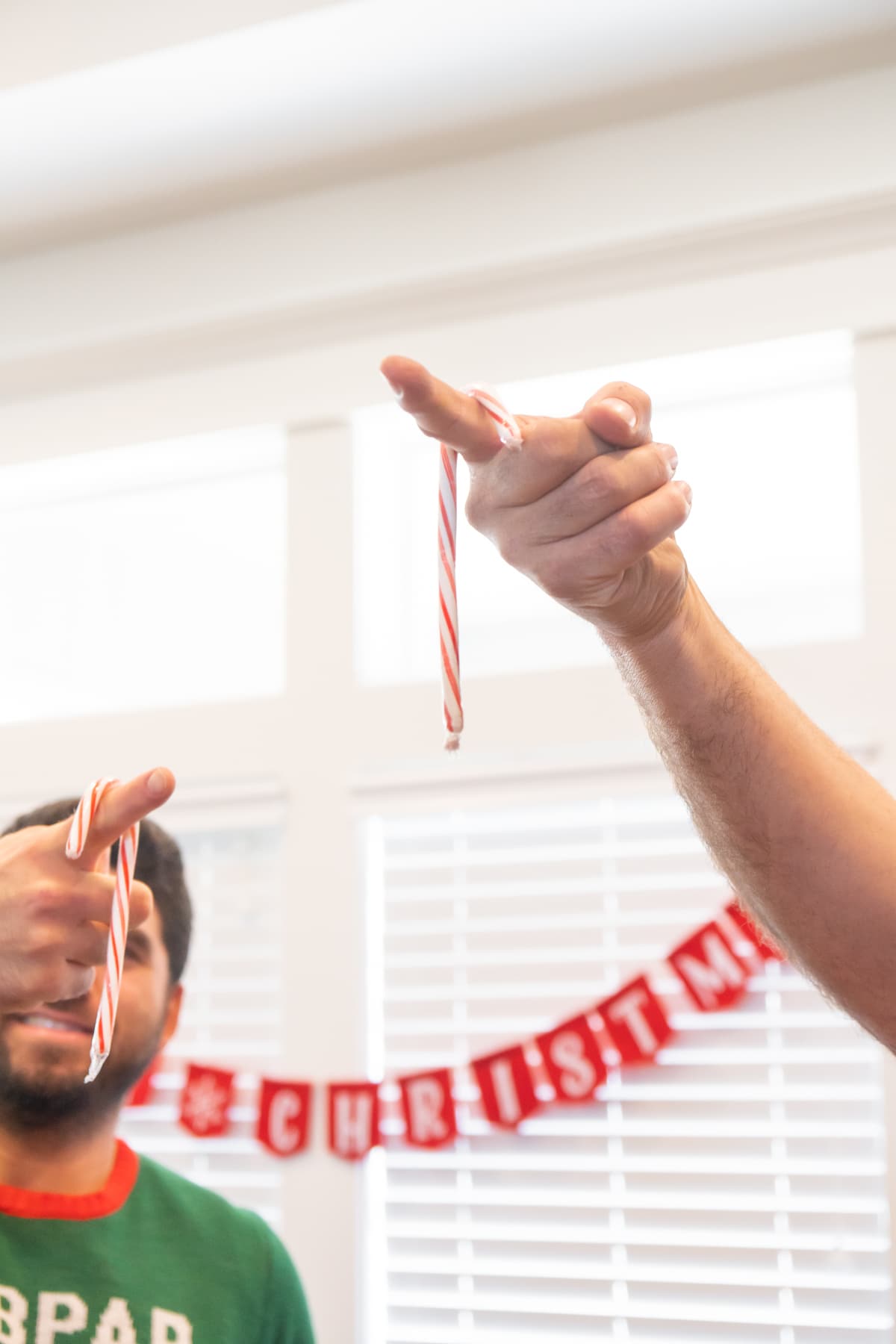 Two people holding candy canes on their fingers