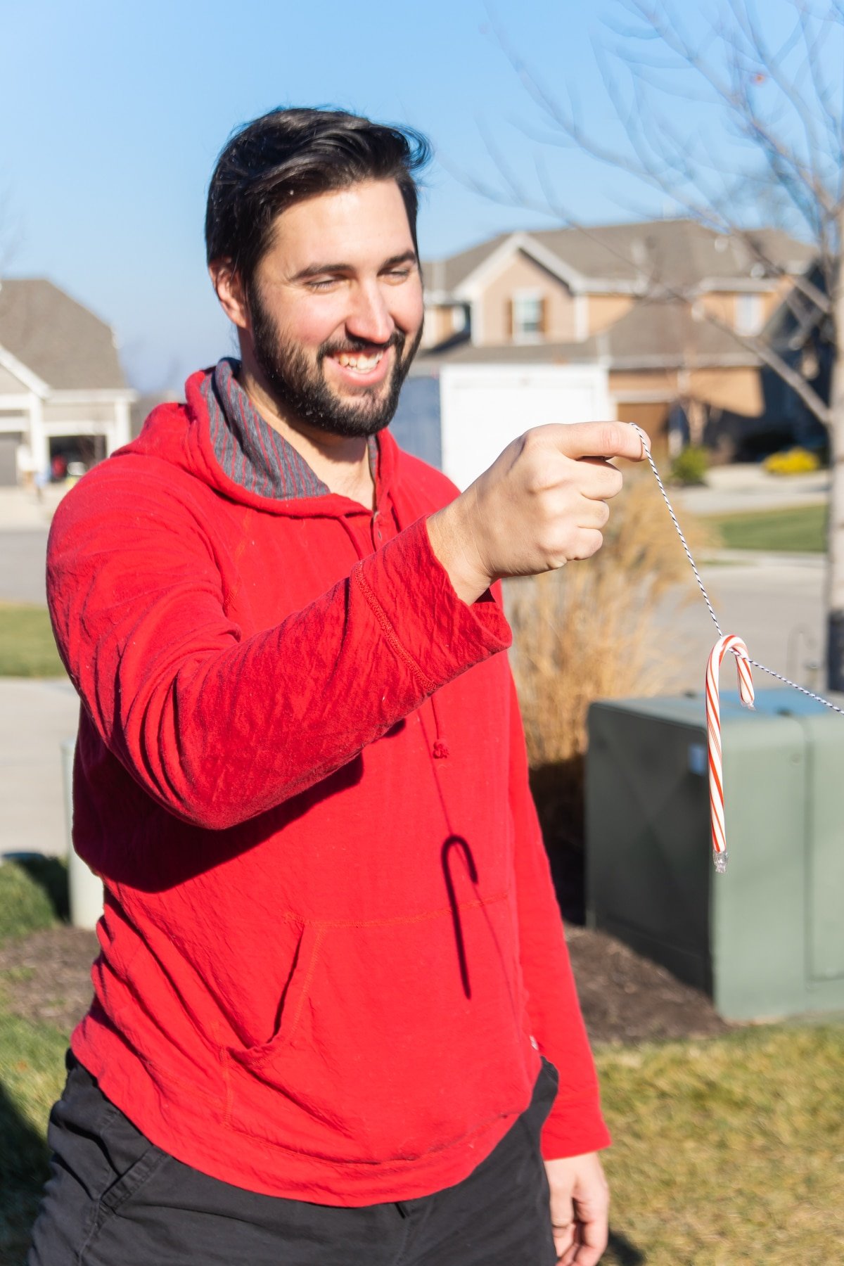 Man in a red sweatshirt holding a candy cane on a string