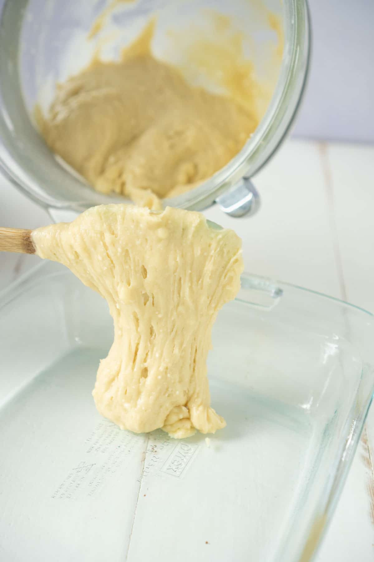 Cherry cake batter being poured into a glass pan