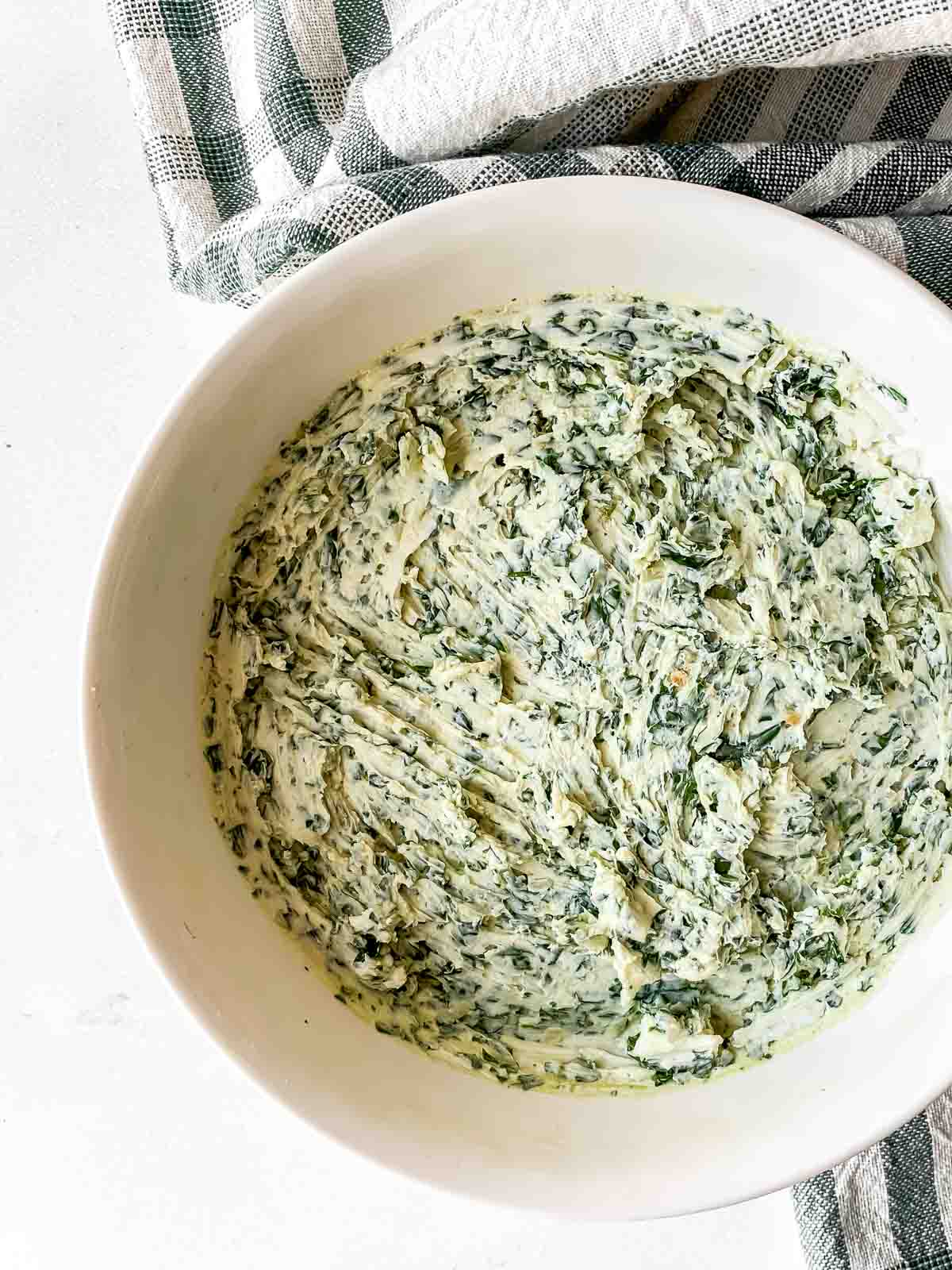 Herbs and cream cheese mixed in a white bowl