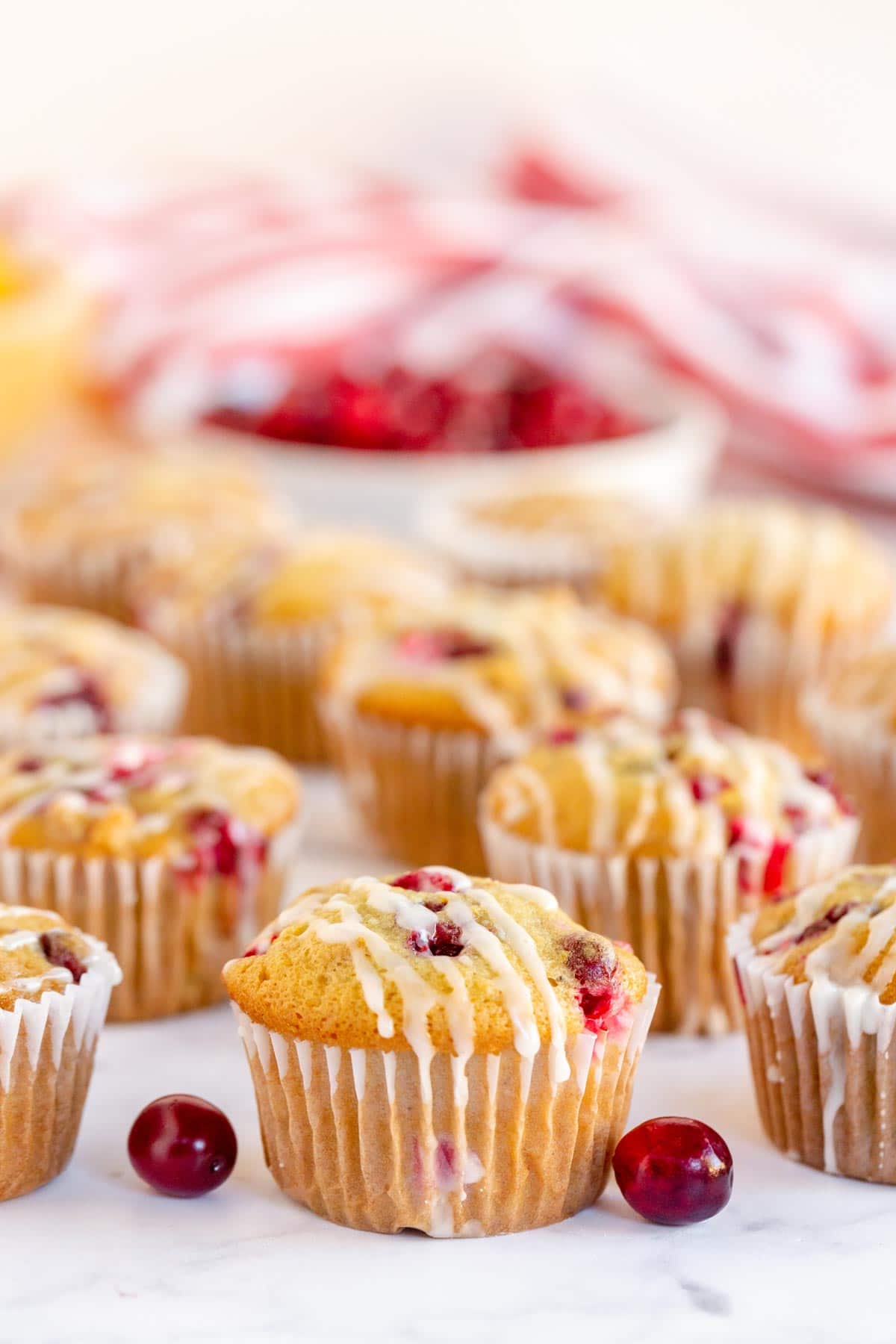A bunch of cranberry orange muffins with glaze in a row