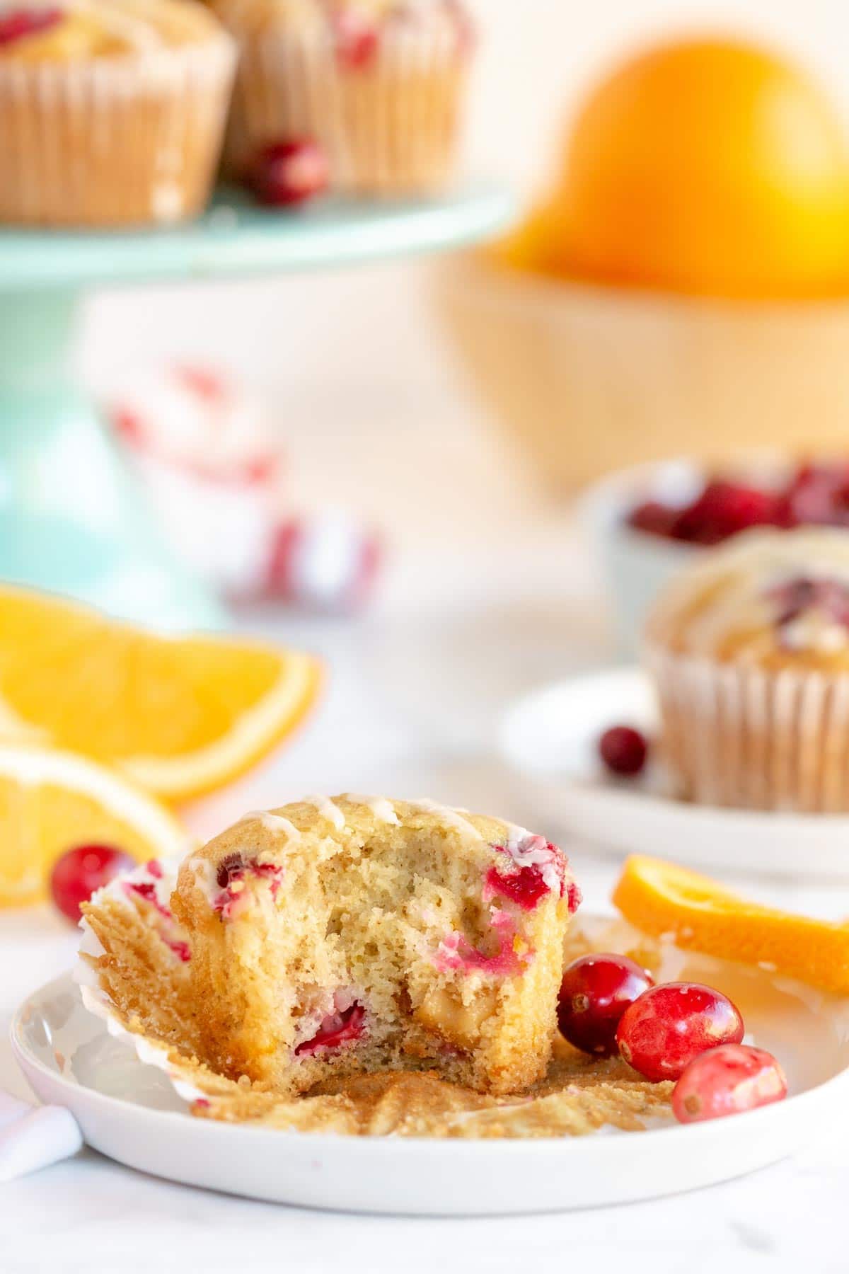 Cranberry orange muffin on a white plate with a bite out of it