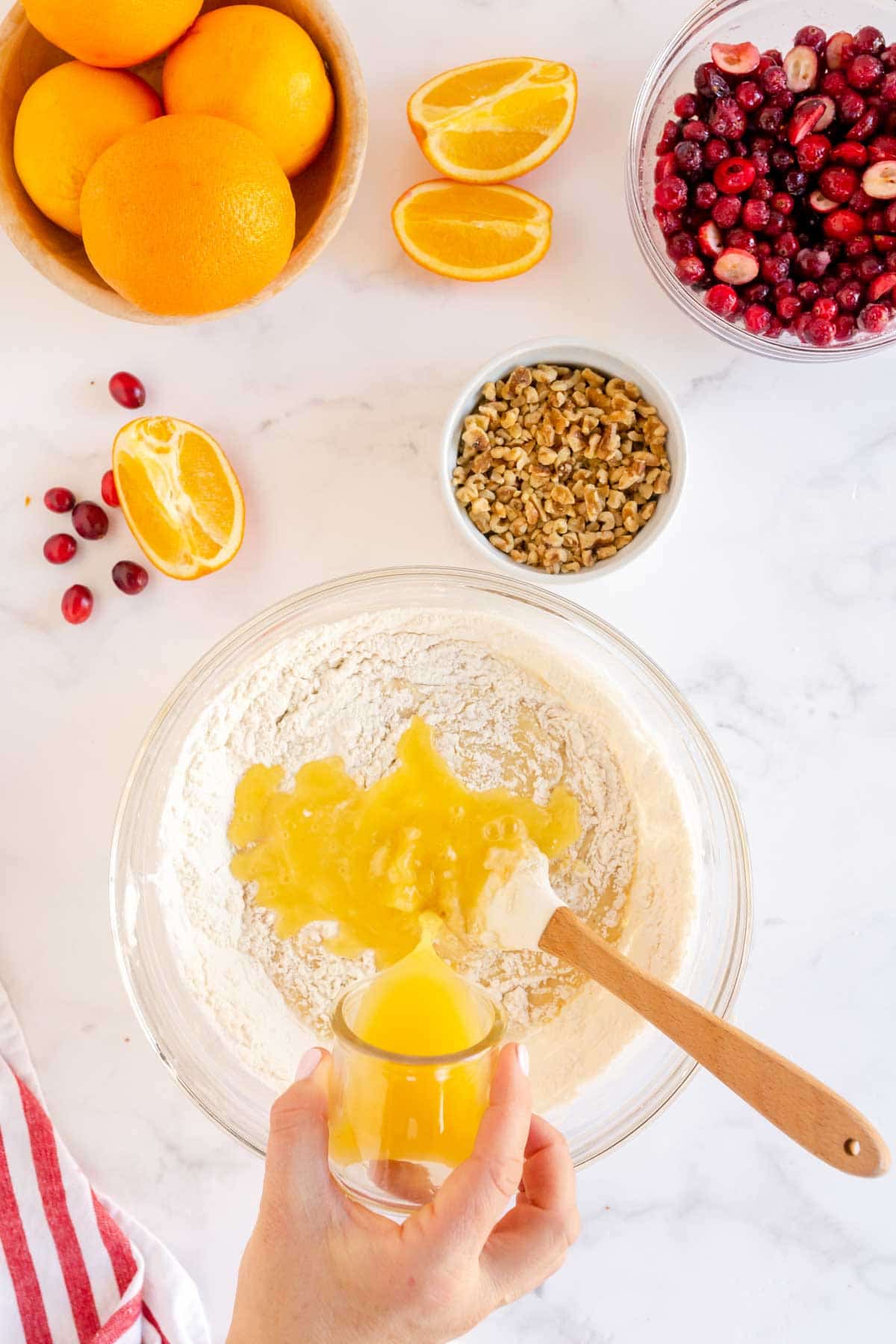 Woman's hand pouring orange juice into a glass bowl