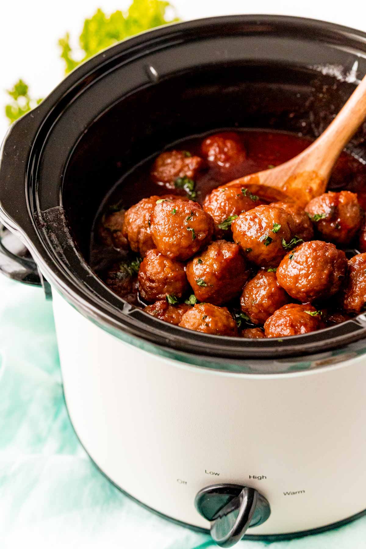 White crockpot with grape jelly meatballs inside