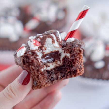 Woman's hand holding a hot chocolate cupcake with a bite taken out of it