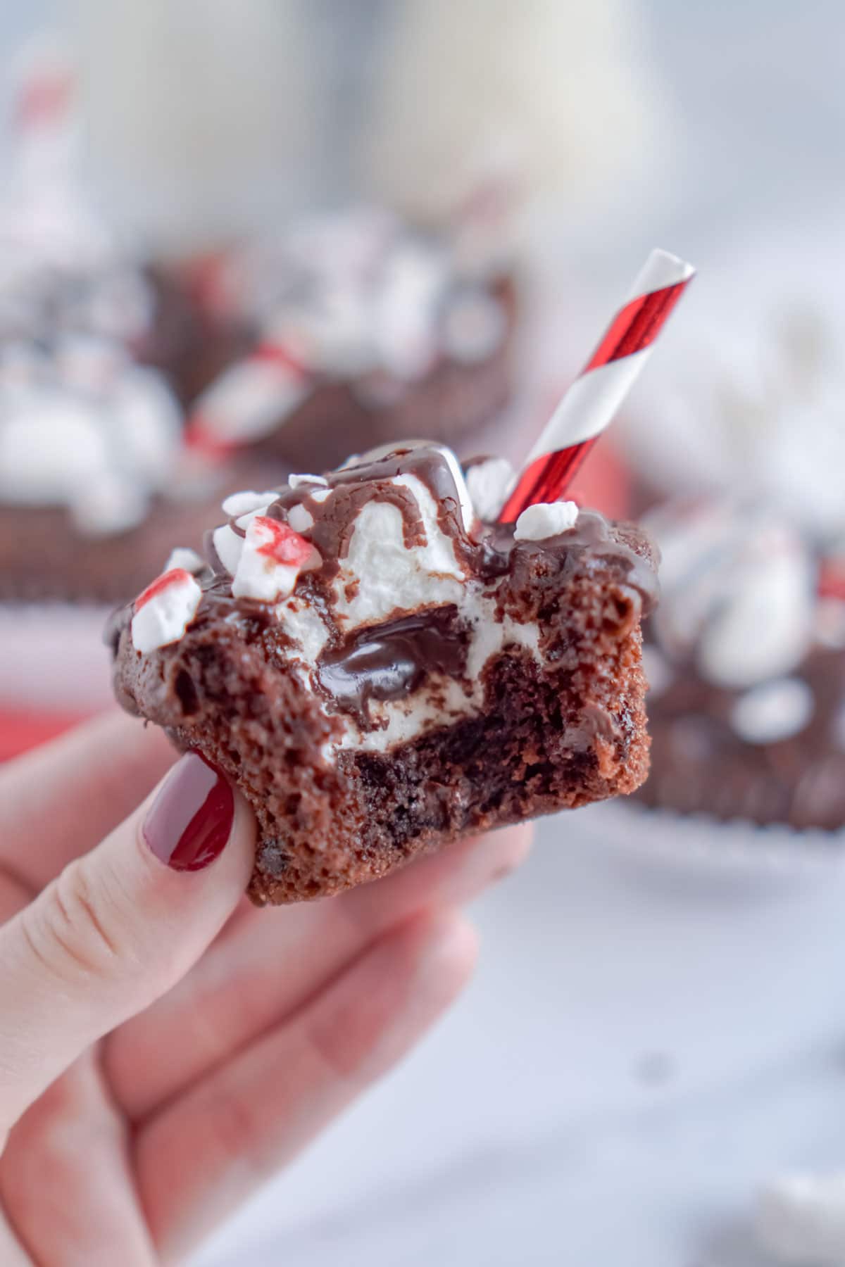 Woman's hand holding a hot chocolate cupcake with a bite taken out of it