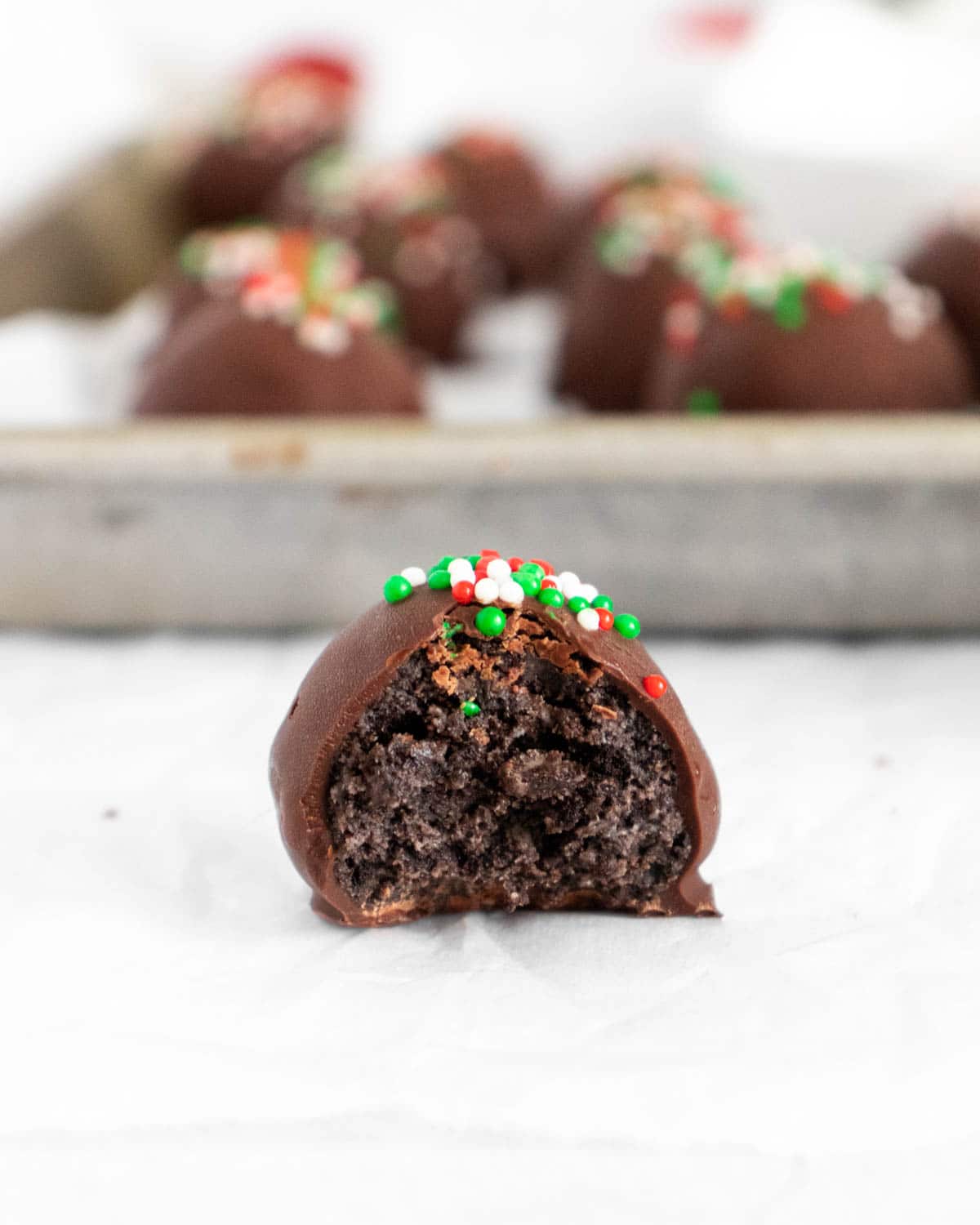 One Oreo truffle with a bite out of it with a pile of Oreo truffles in the back