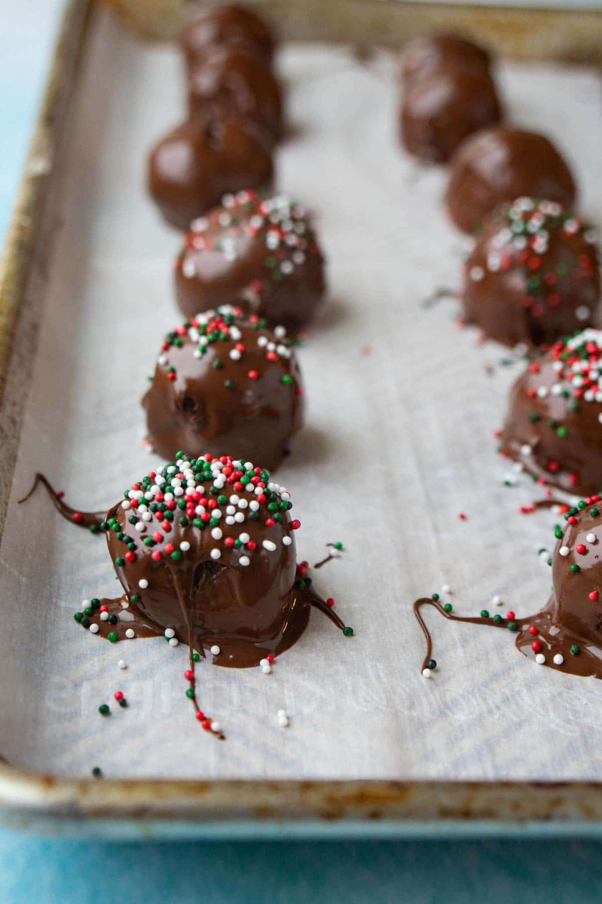 Oreo truffles with Christmas sprinkles on a piece of parchment paper