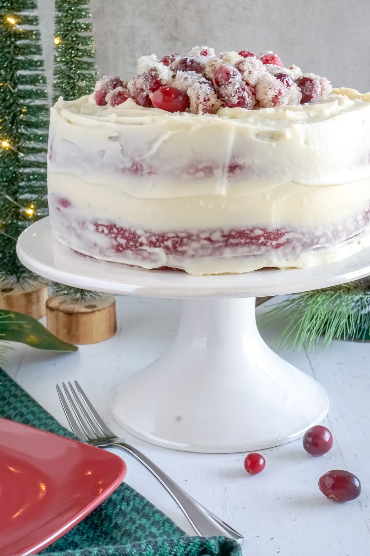 sugared cranberries on top of a naked red velvet cake