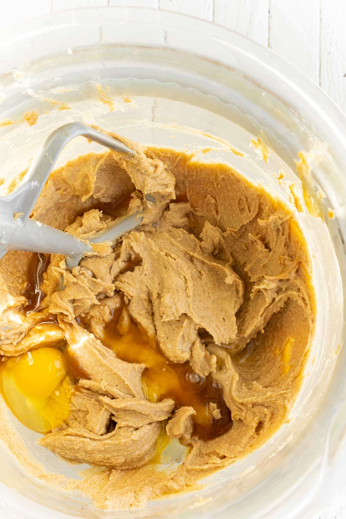 Glass mixing bowl with sugars, peanut butter, and eggs