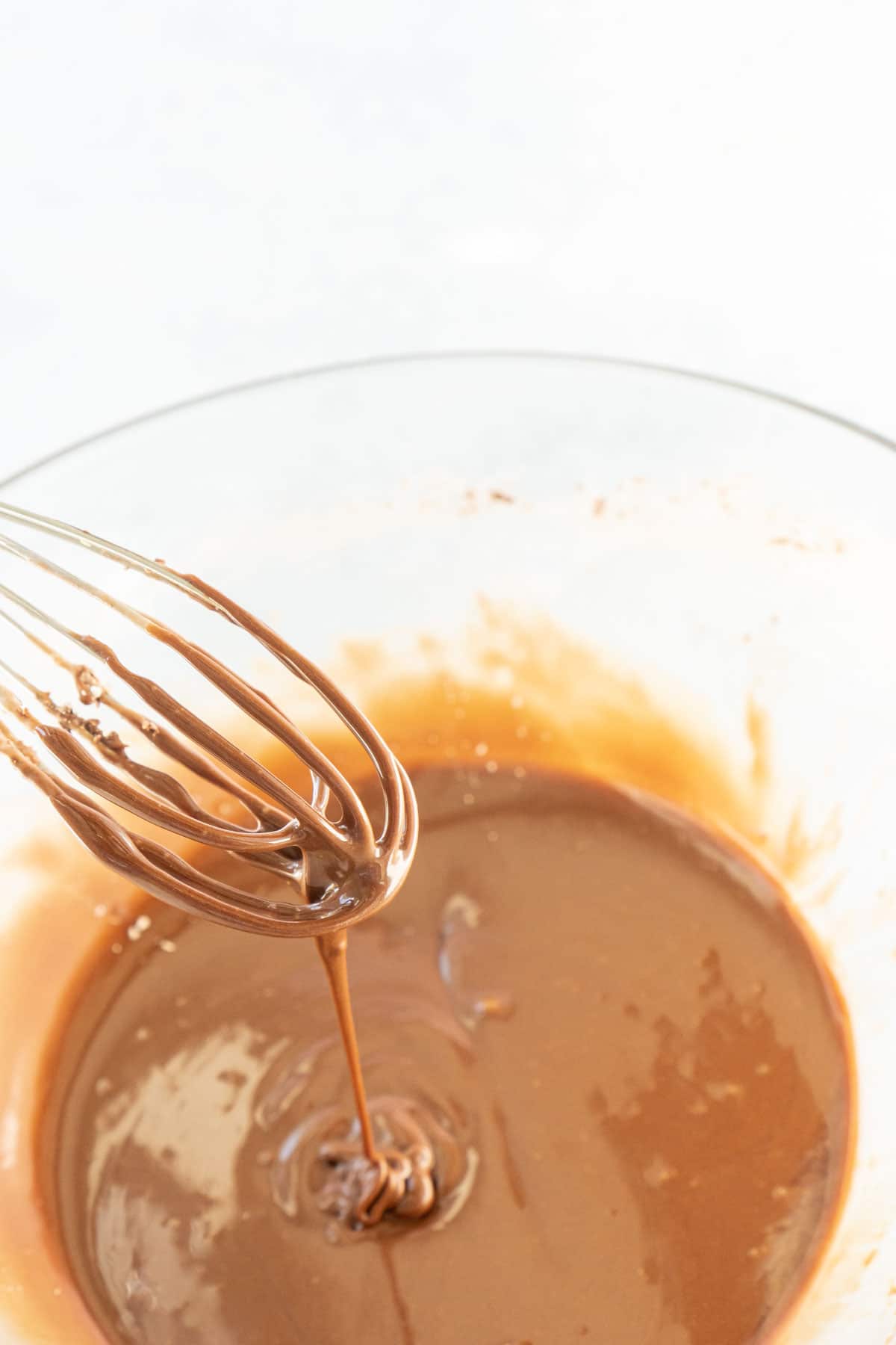 Whisk in a bowl with chocolate glaze