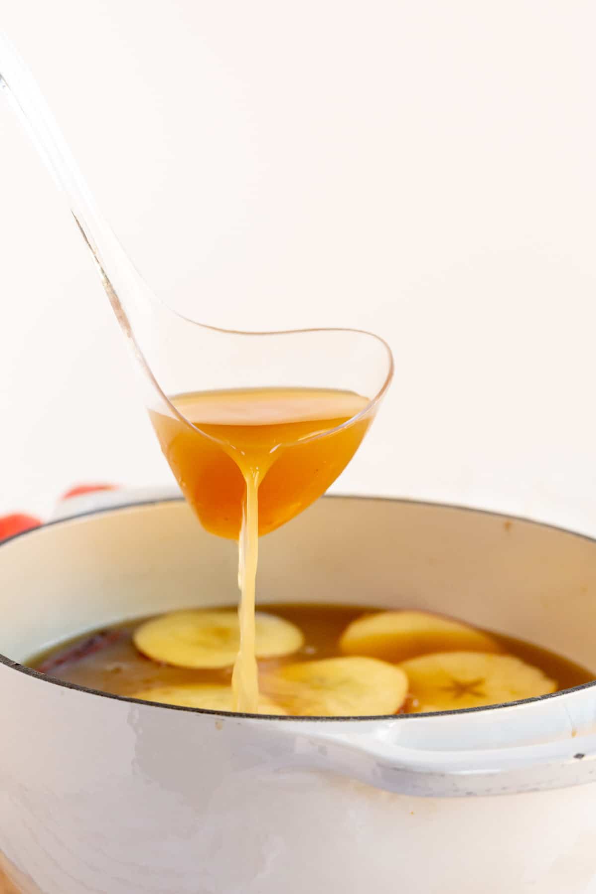 Ladle pouring spiced apple cider into a bowl
