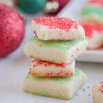 stack of sugar cookie bites with ornaments in the background