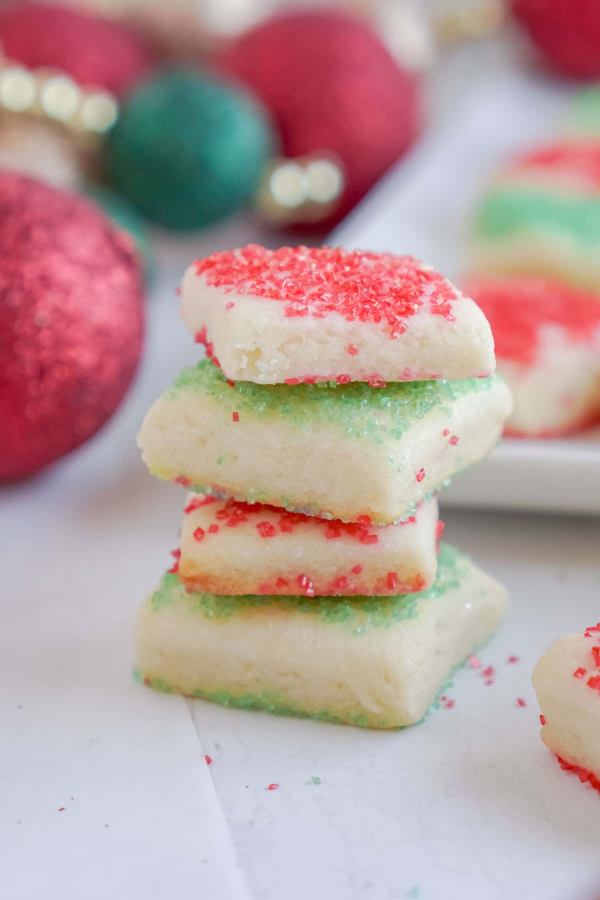 stack of sugar cookie bites with ornaments in the background