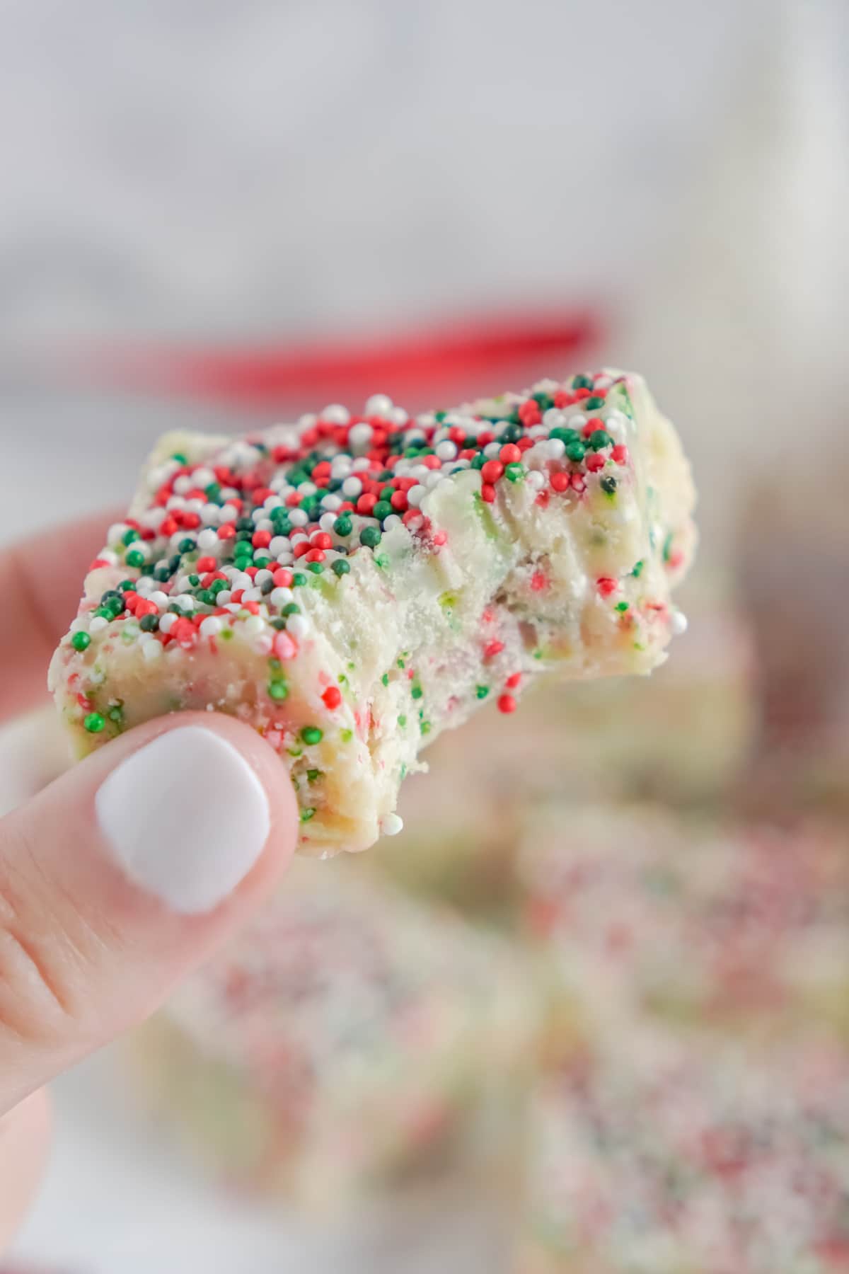 Woman's hand holding white chocolate fudge with sprinkles