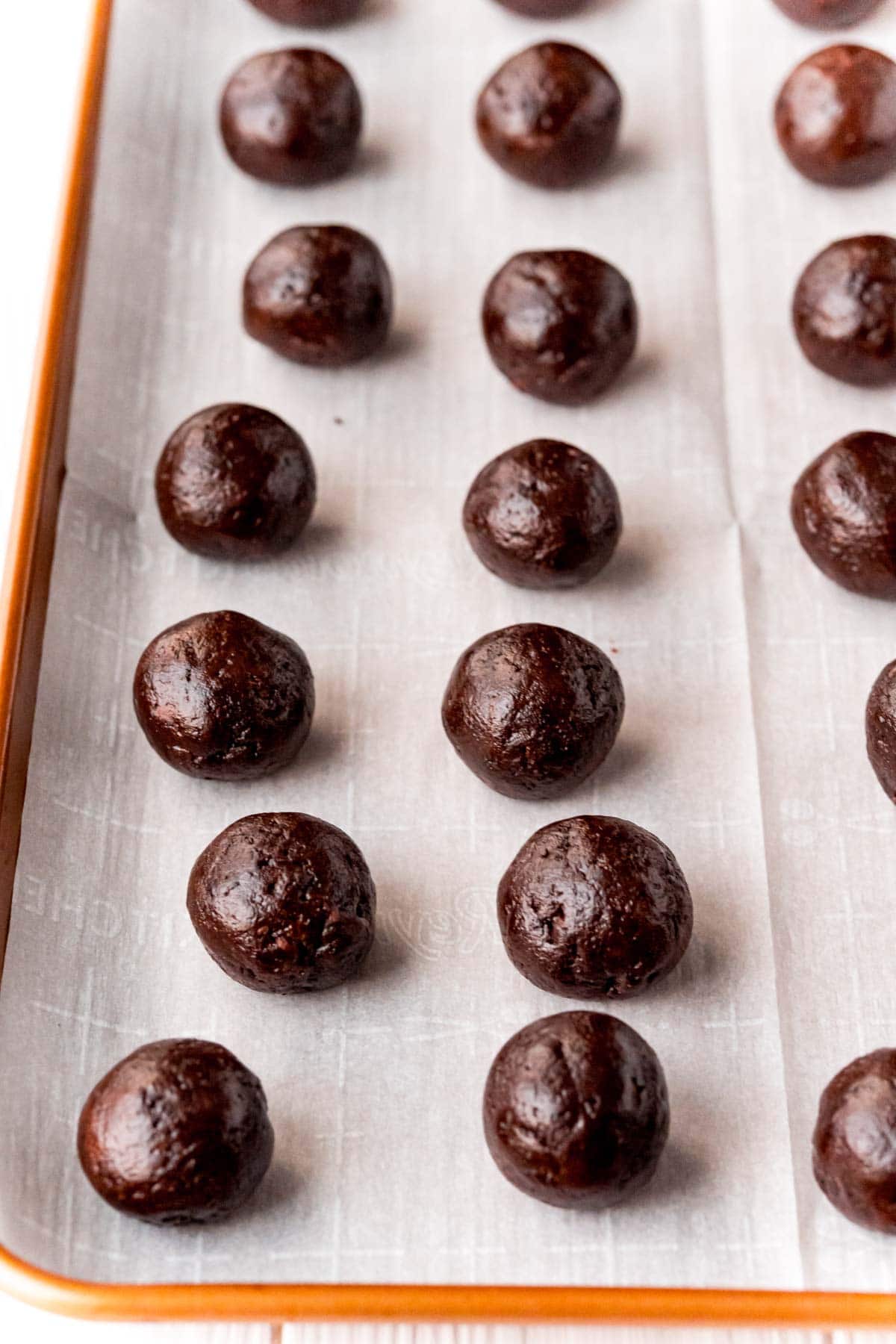 Brownie balls on a piece of parchment paper on a baking sheet