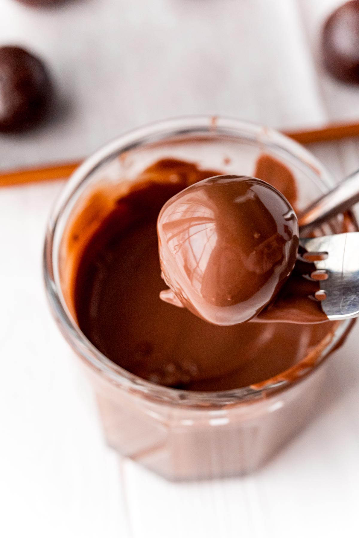 Fork holding a brownie ball above a glass of chocolate