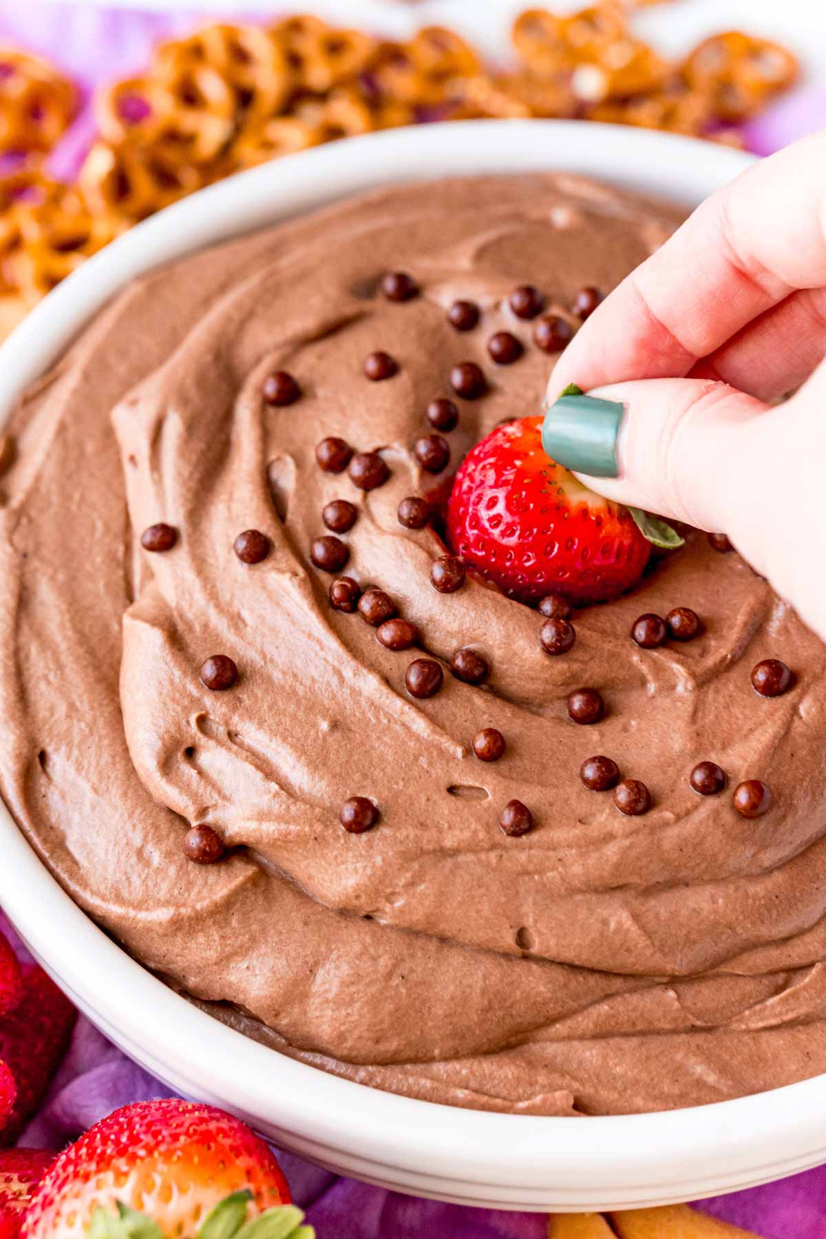 Woman's hand dipping strawberry into brownie batter dip