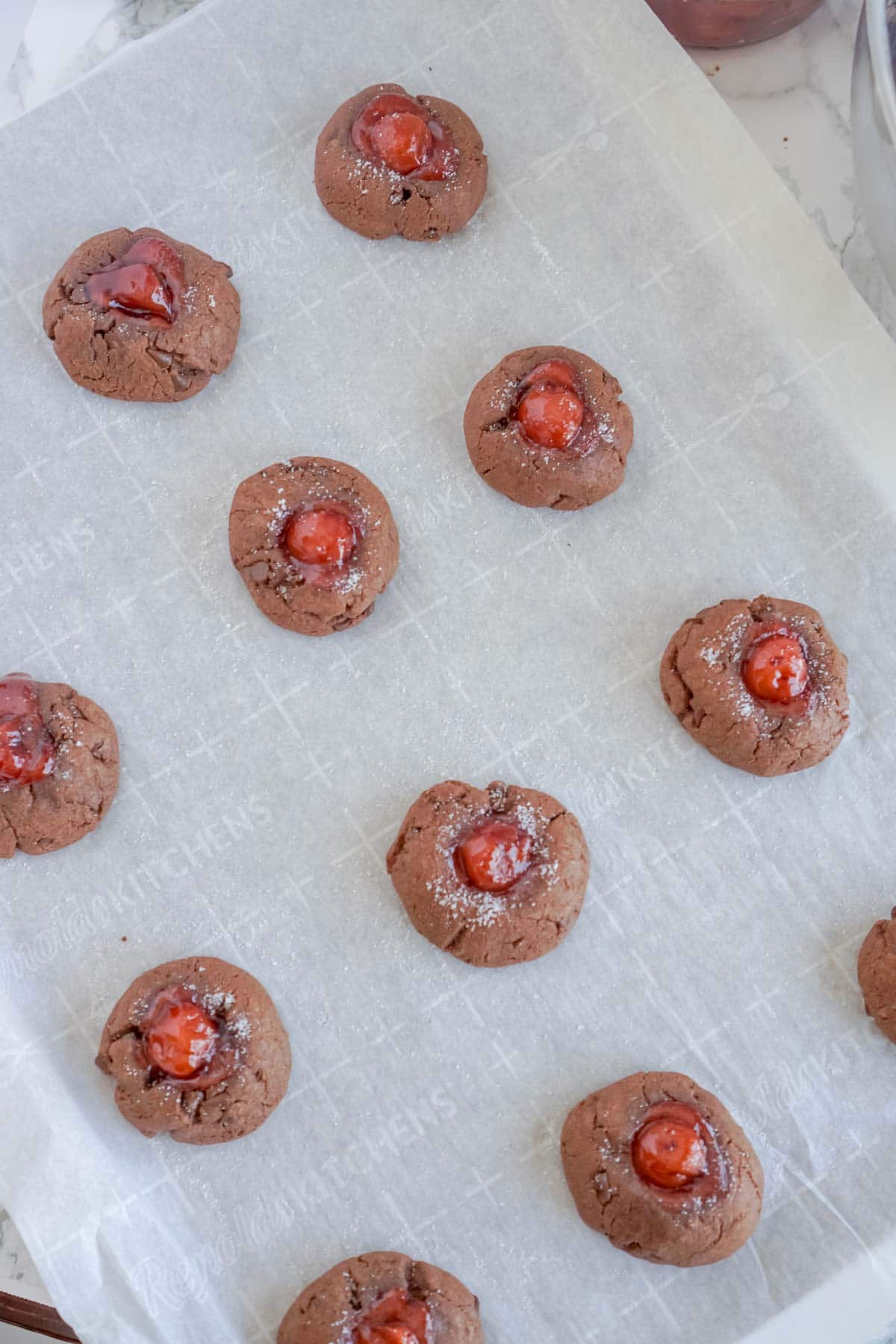 Chocolate thumbprint cookies on a baking sheet