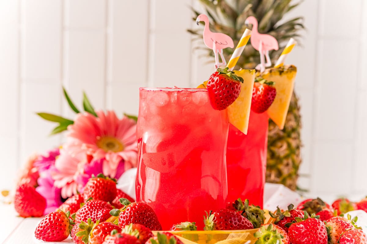 Two red cotton candy drinks with a pineapple in the background