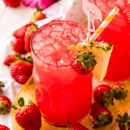 Red cotton candy drink with ice and a pineapple wedge garnish