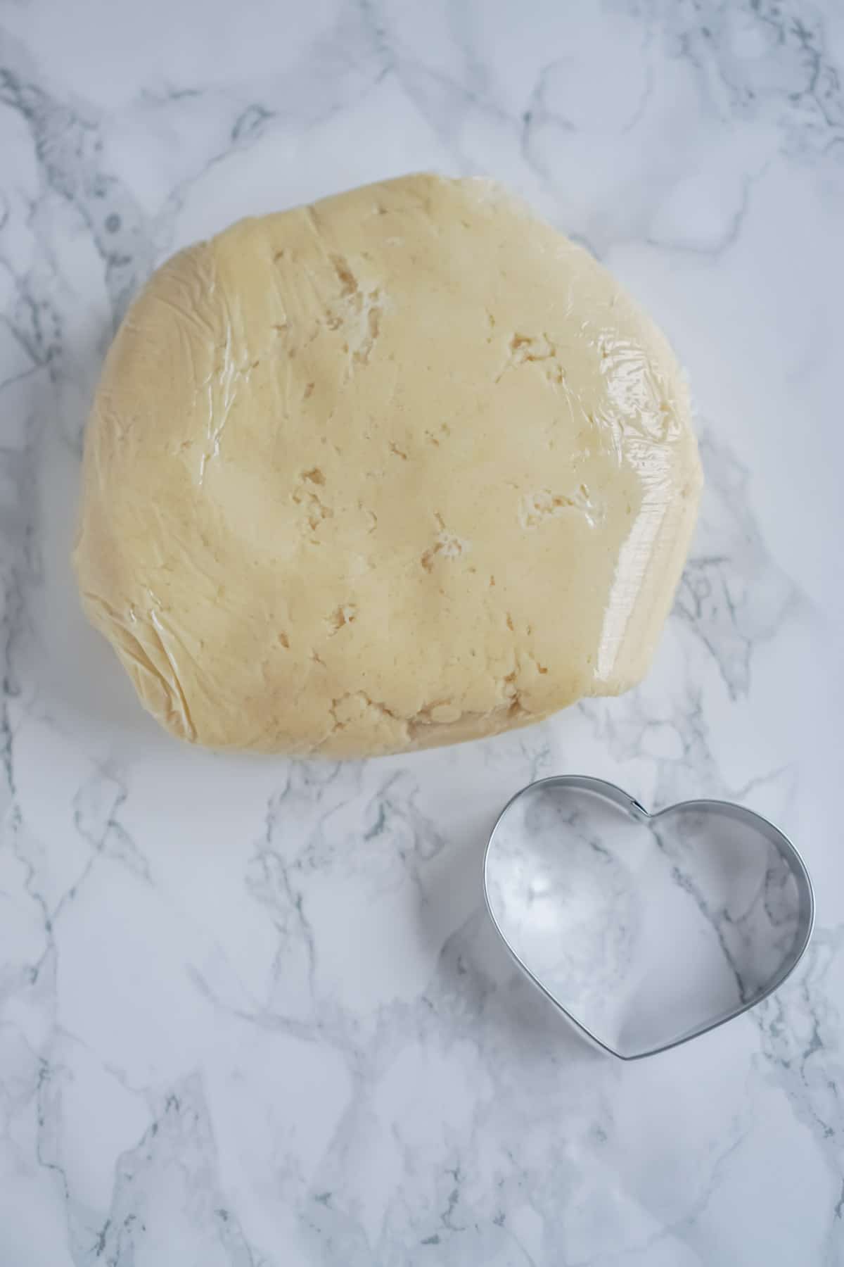 Cream cheese sugar cookie dough with a heart cookie cutter next to it