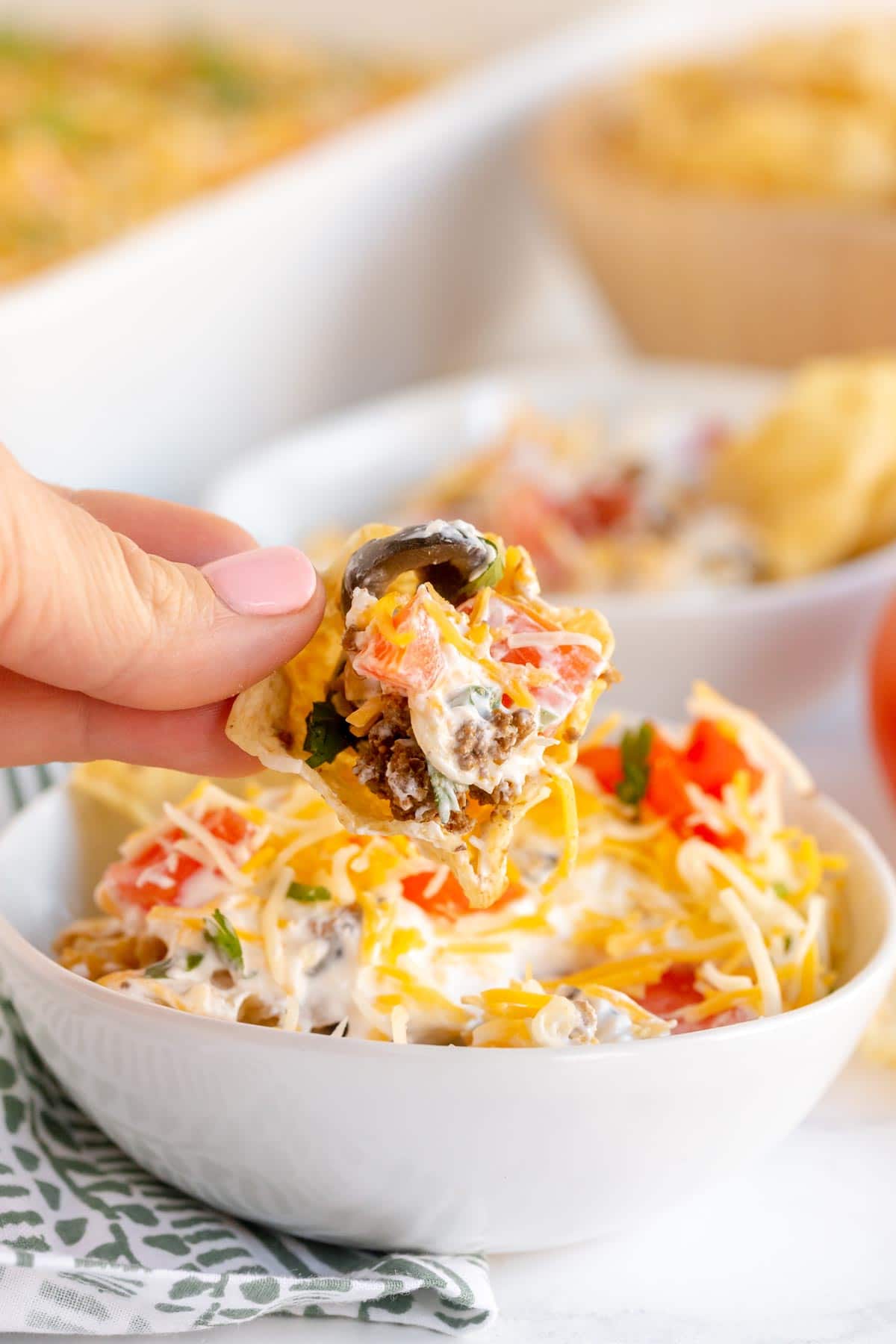 Woman's hand holding a chip with taco dip