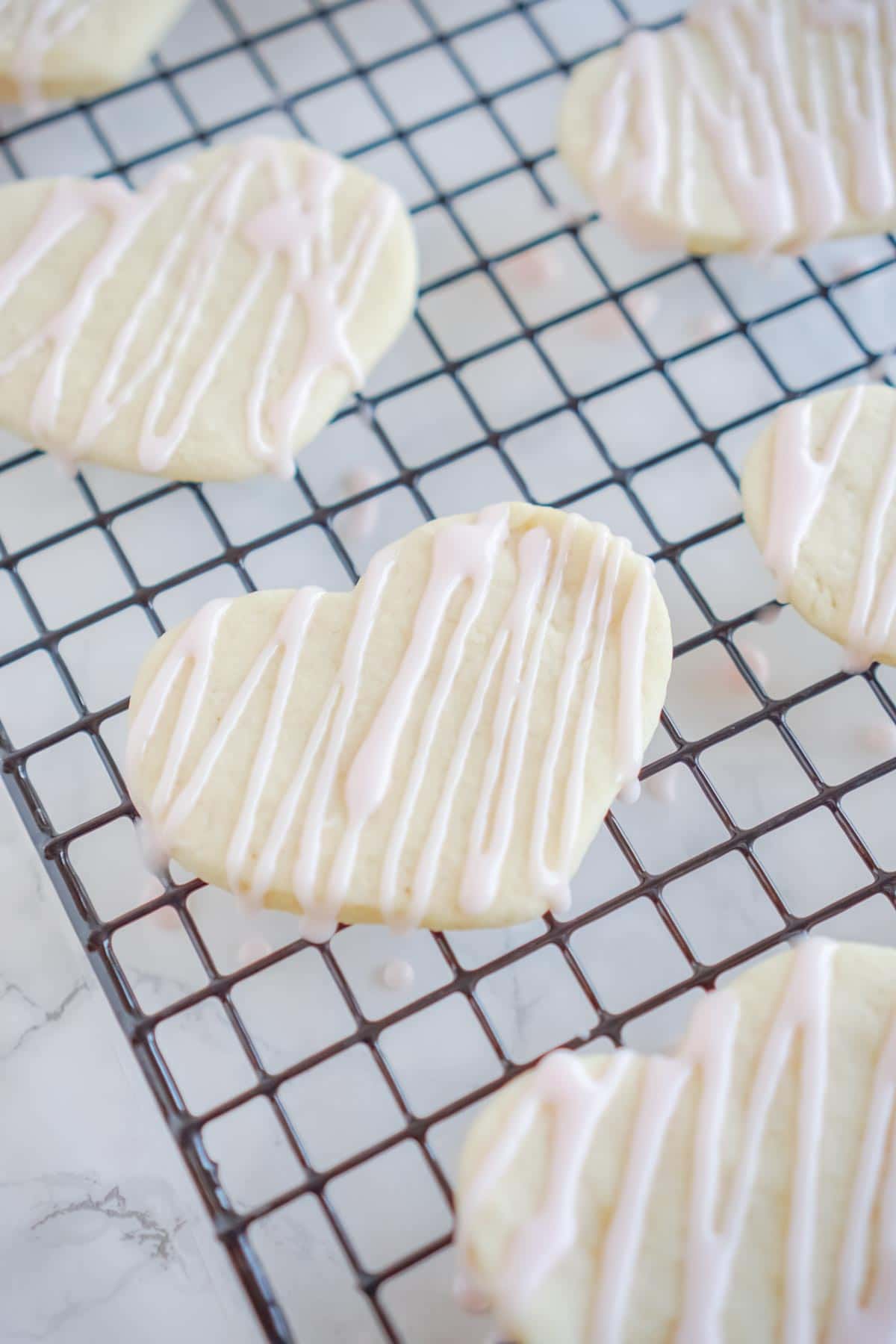 heart shaped cookies with sugar cookie icing on a baking rack