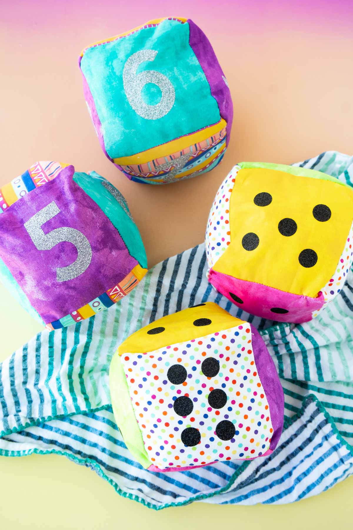 Two sets of fabric DIY dice on a colored background