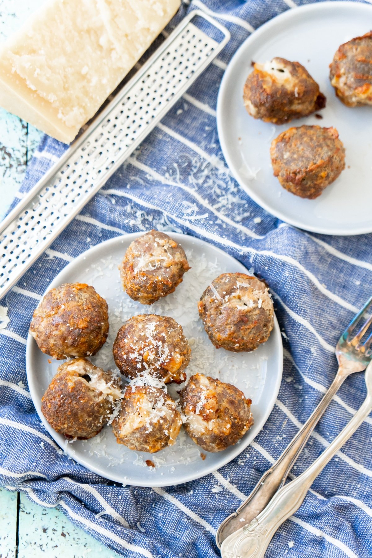 Two white plates with cheese stuffed meatballs