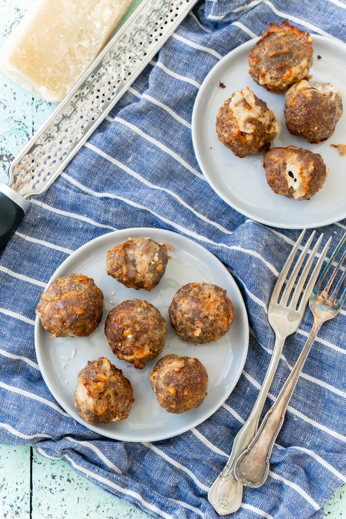 Plates of cheese stuffed meatballs with a blue napkin