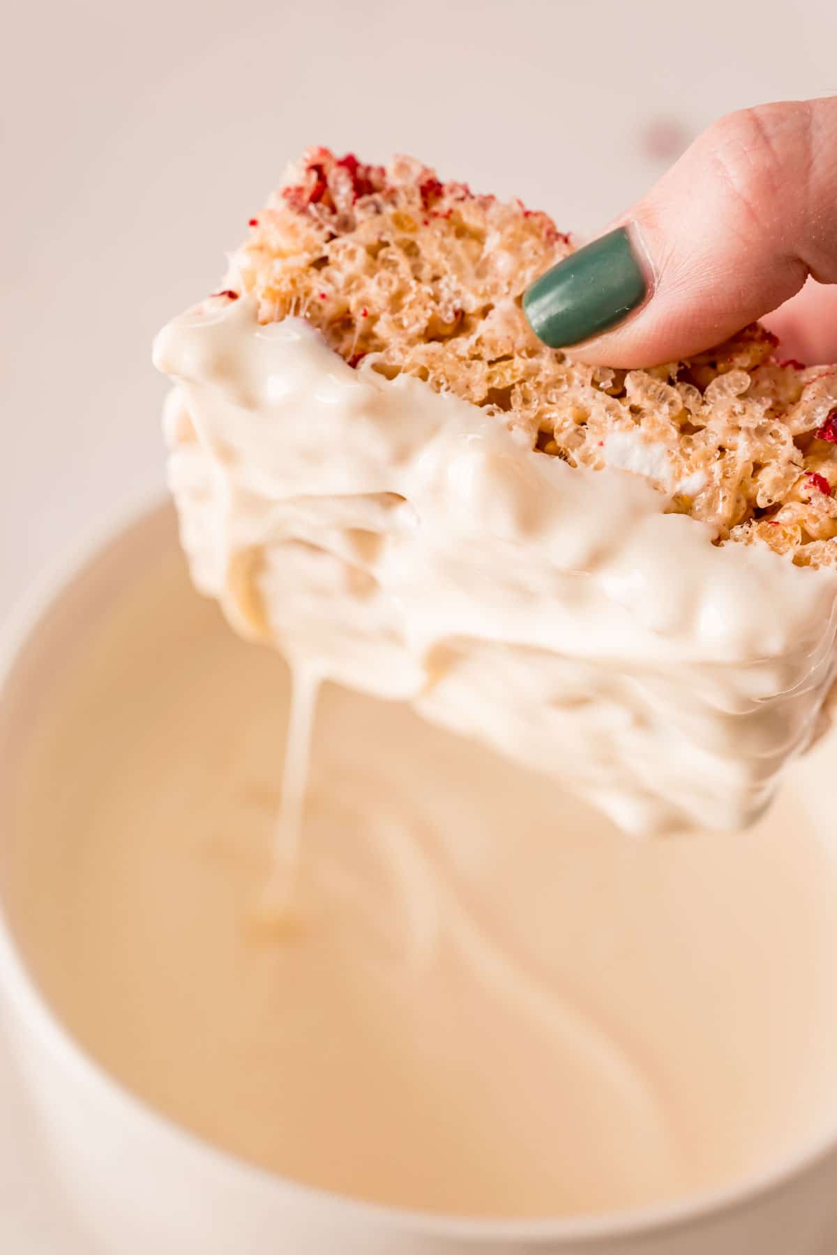 Rice krispie treat being dipped in white chocolate