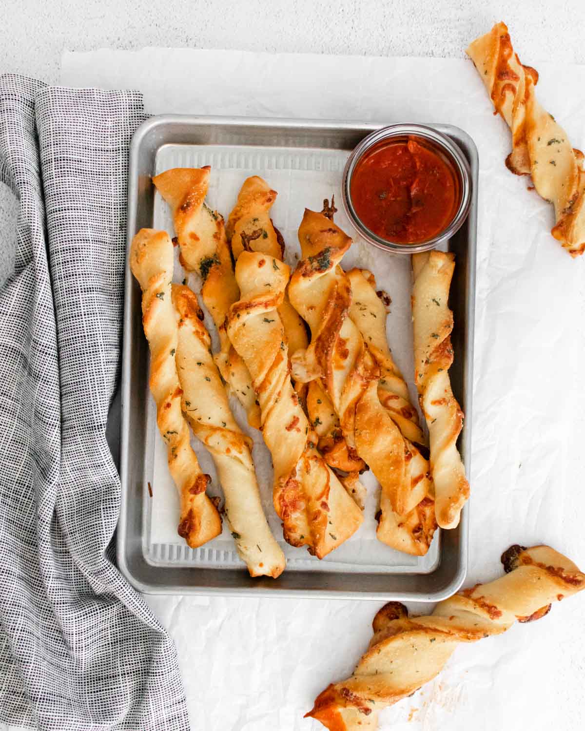 Baking sheet full of pizza twists and pizza sauce