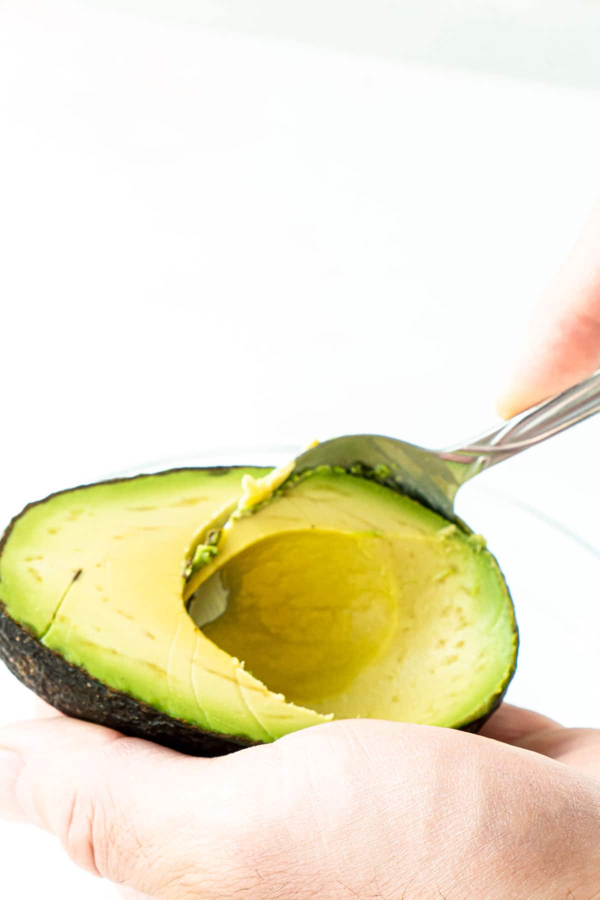 Woman's hand spooning out avocado